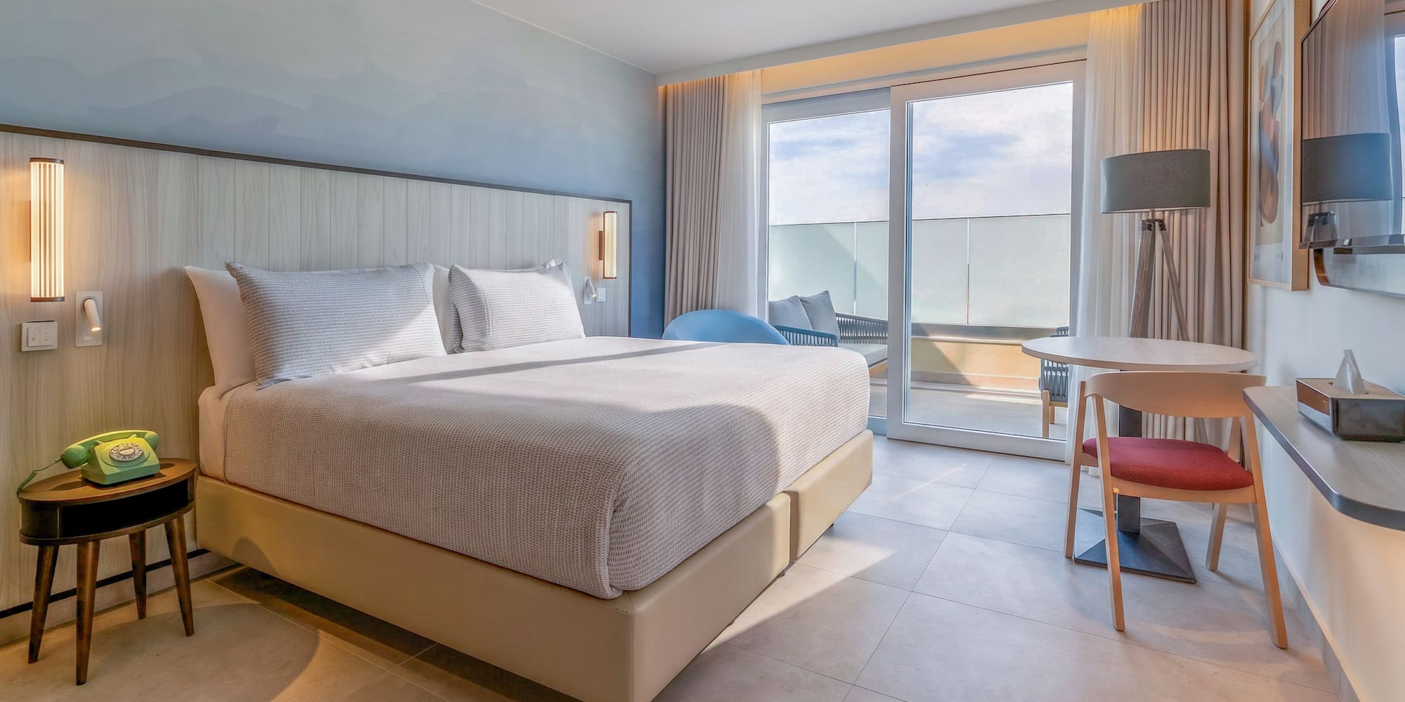Modern hotel room with king bed, balcony, and contemporary design.