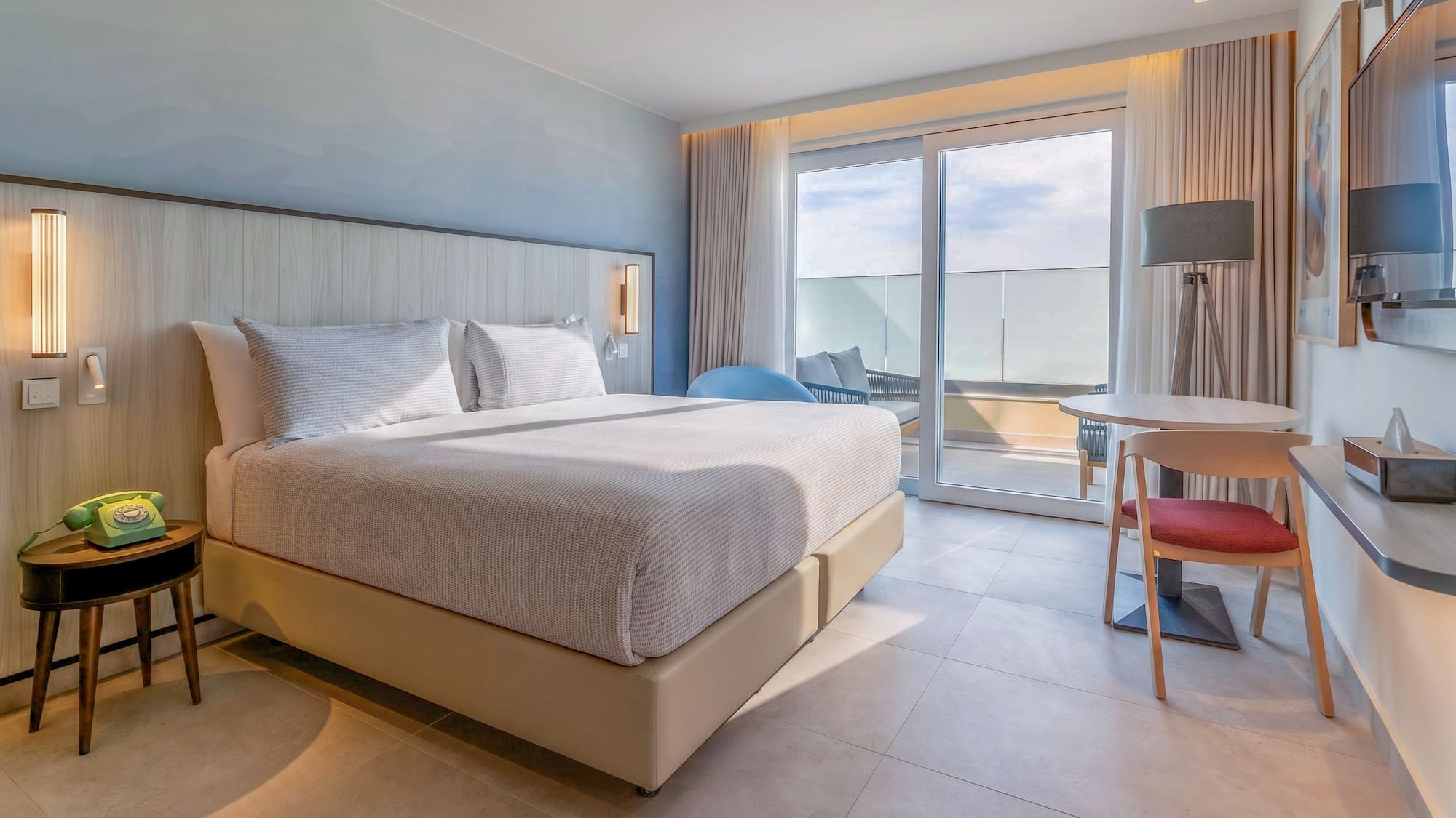 Modern hotel room with king bed, balcony, and contemporary design.