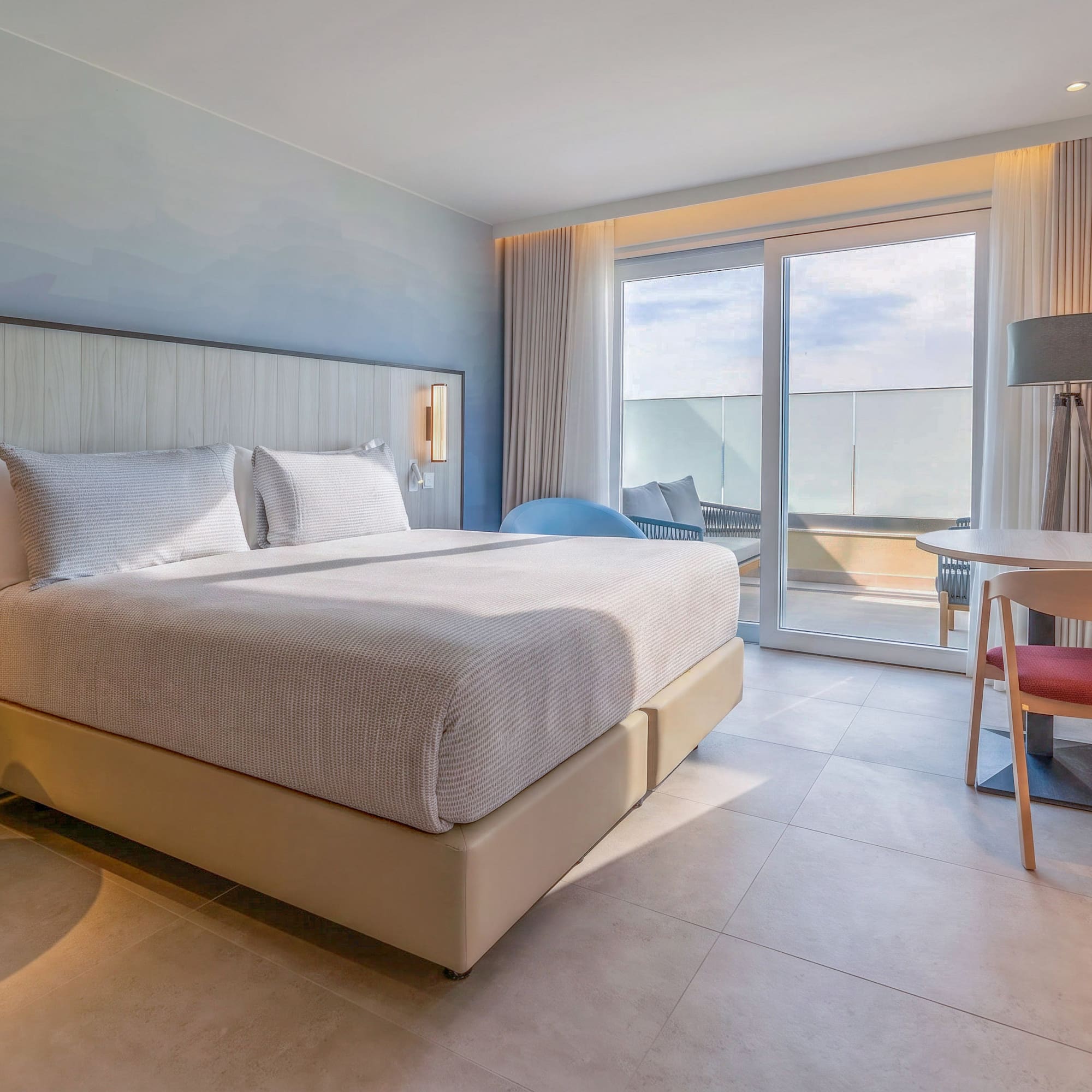 Modern hotel room with king bed, balcony, and contemporary design.