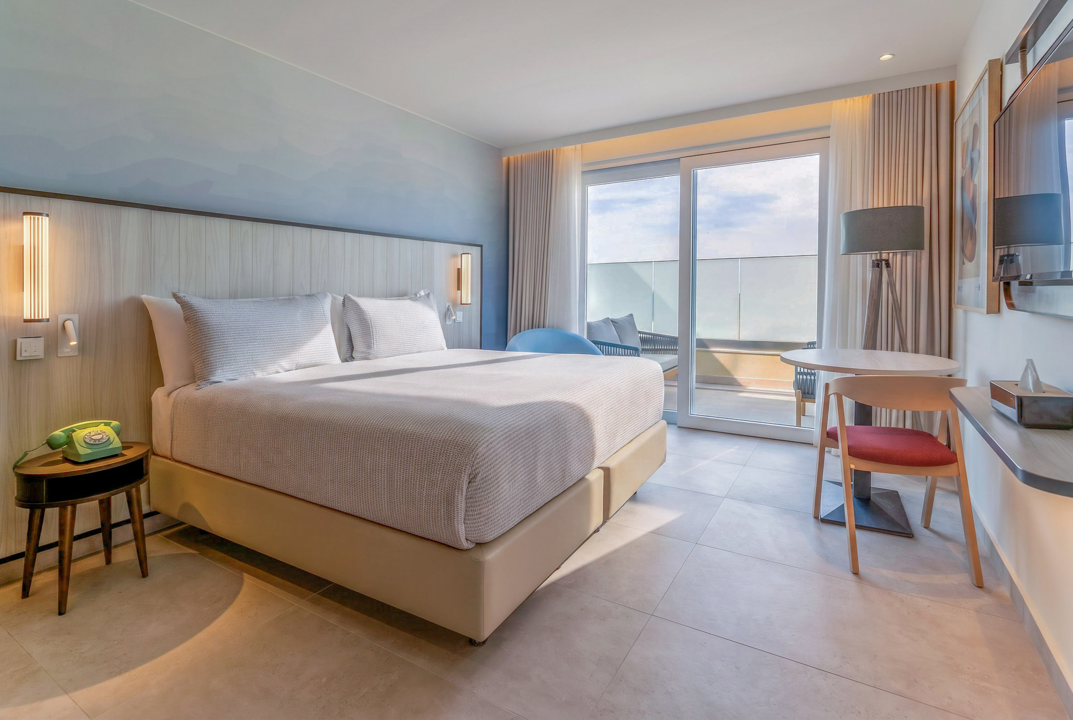 Modern hotel room with king bed, balcony, and contemporary design.