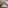 Modern hotel room with cozy bed, wood accents, and sloping ceiling.