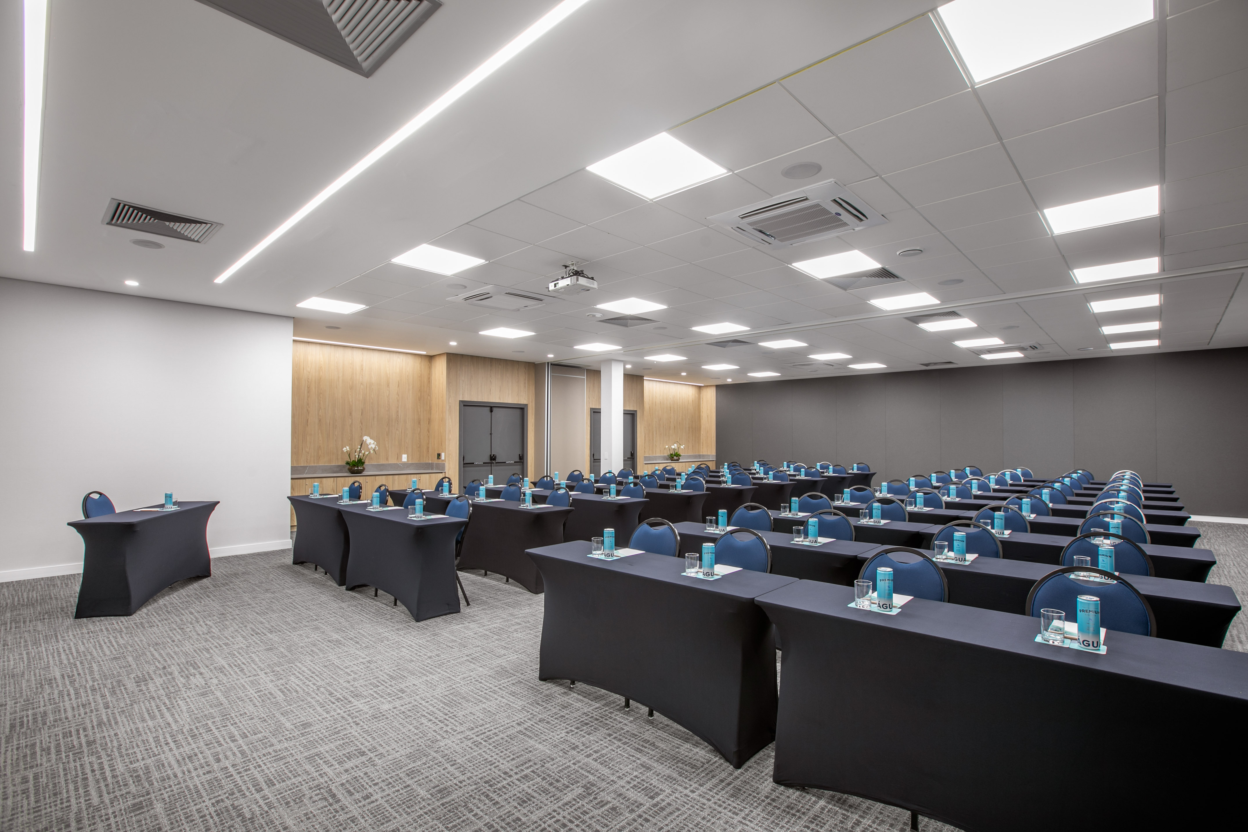 Modern conference room with blue chairs, black tables, and projector.