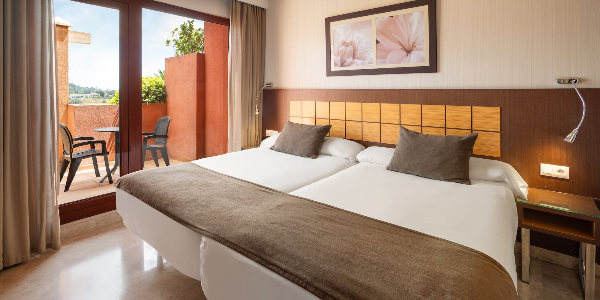 Hotel twin room with private balcony, brown bedding, and tiled floor.
