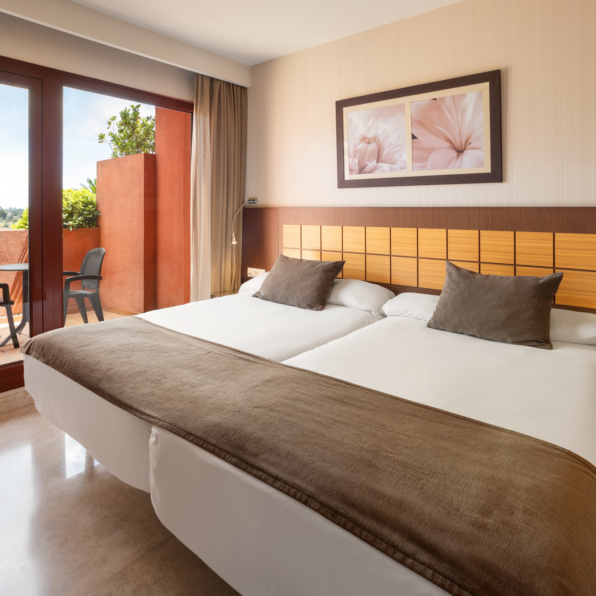 Hotel twin room with private balcony, brown bedding, and tiled floor.