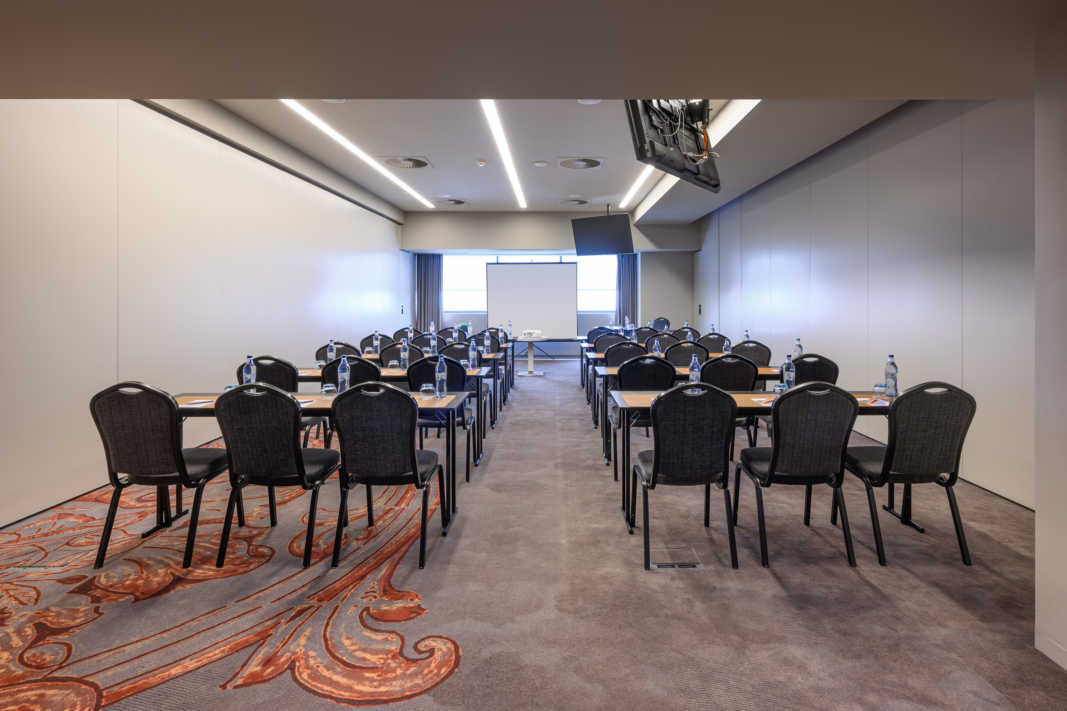 Empty modern meeting room with projection screen and classroom style seating.