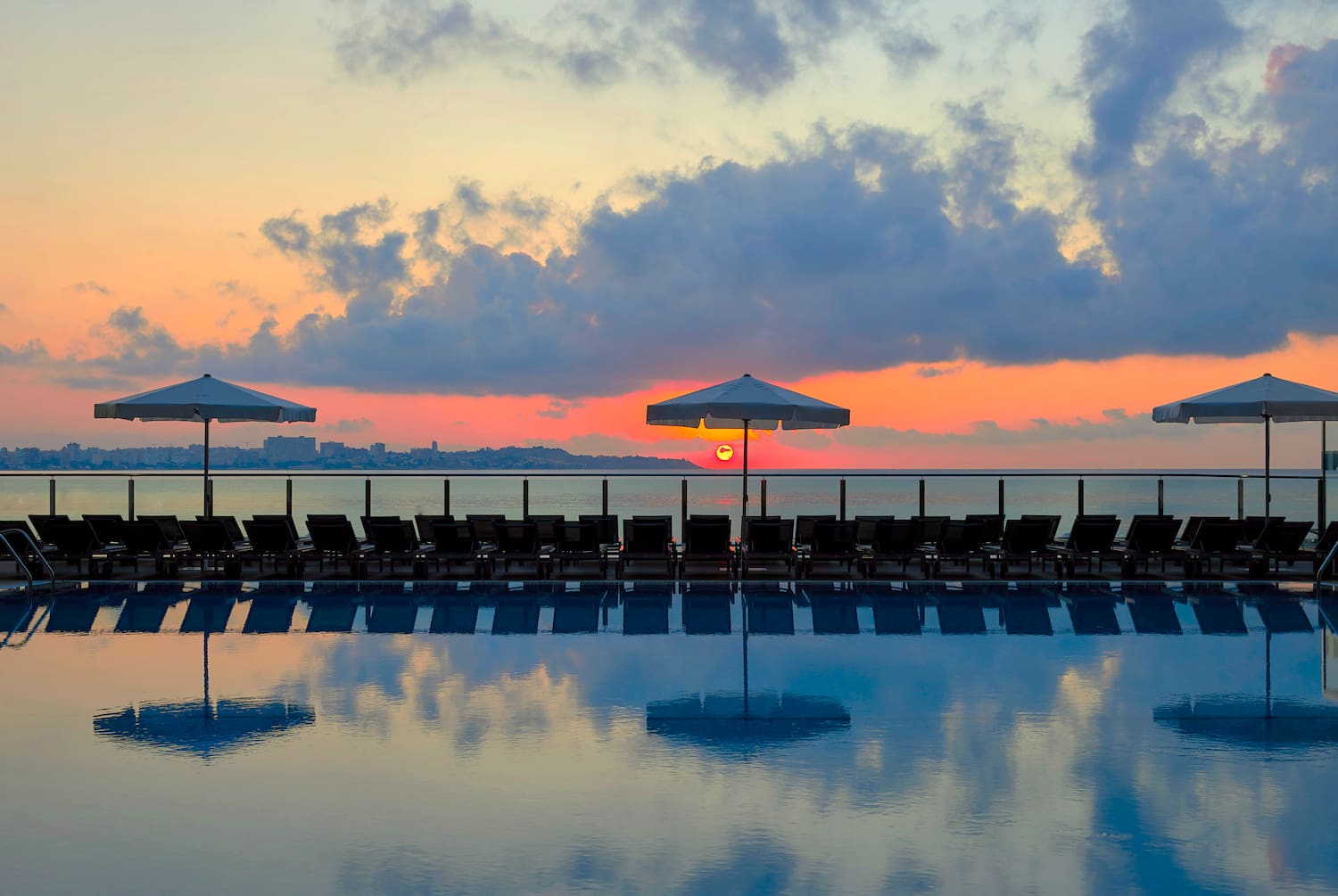 a pool with umbrellas and chairs in the foreground