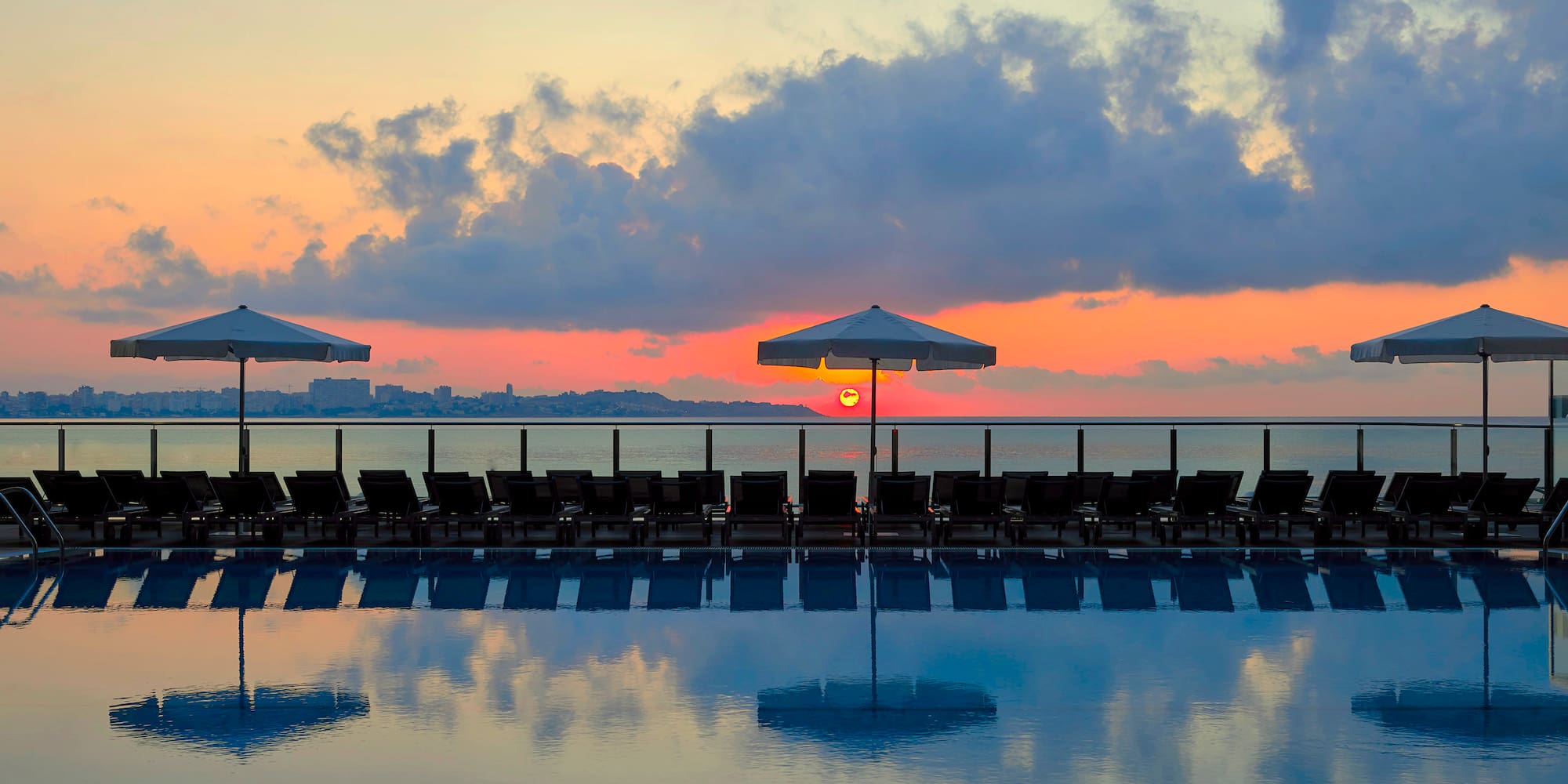 a pool with umbrellas and chairs in the foreground