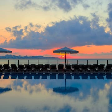 a pool with umbrellas and chairs in the foreground