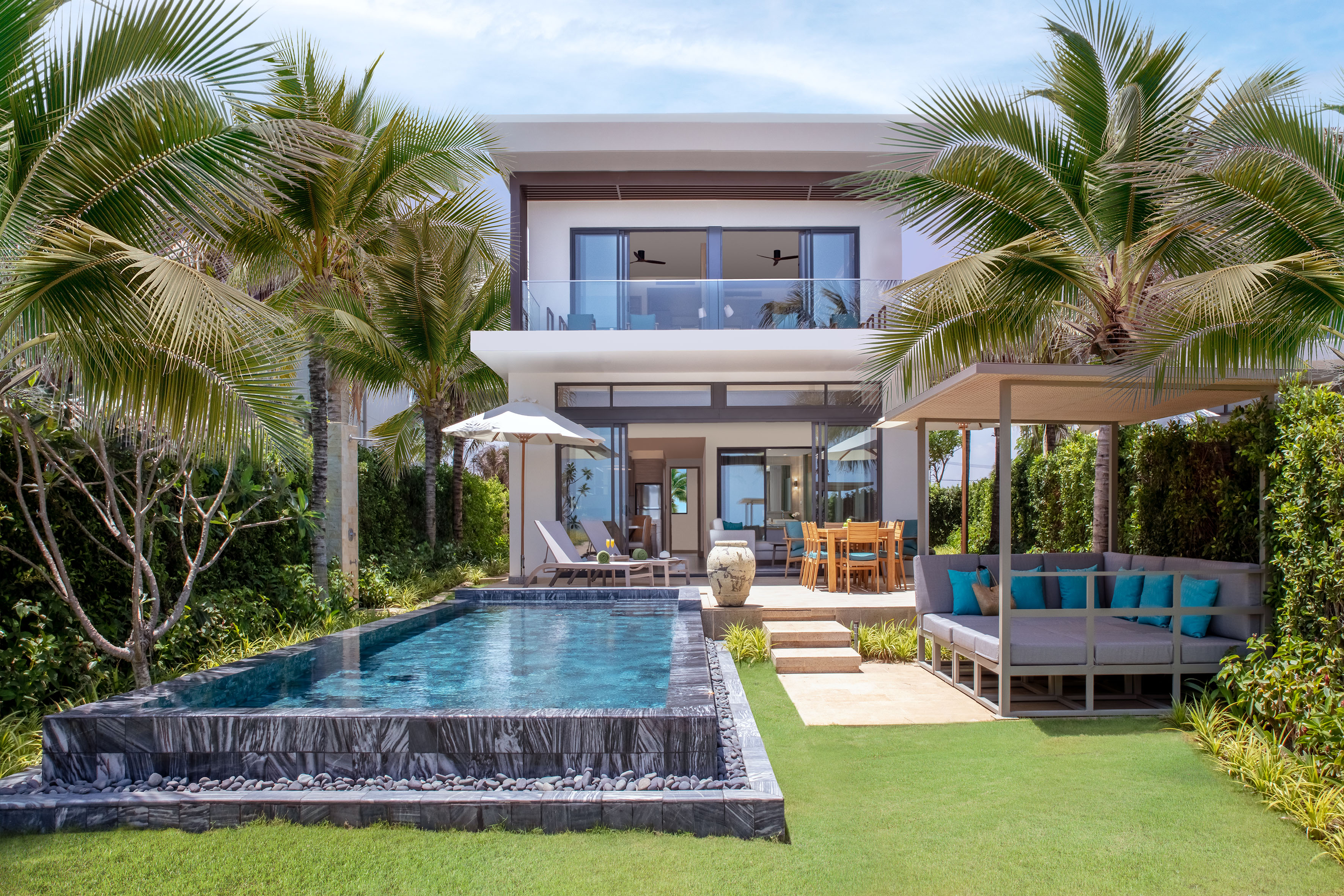 Modern tropical villa with private pool, outdoor living space, and palm trees.