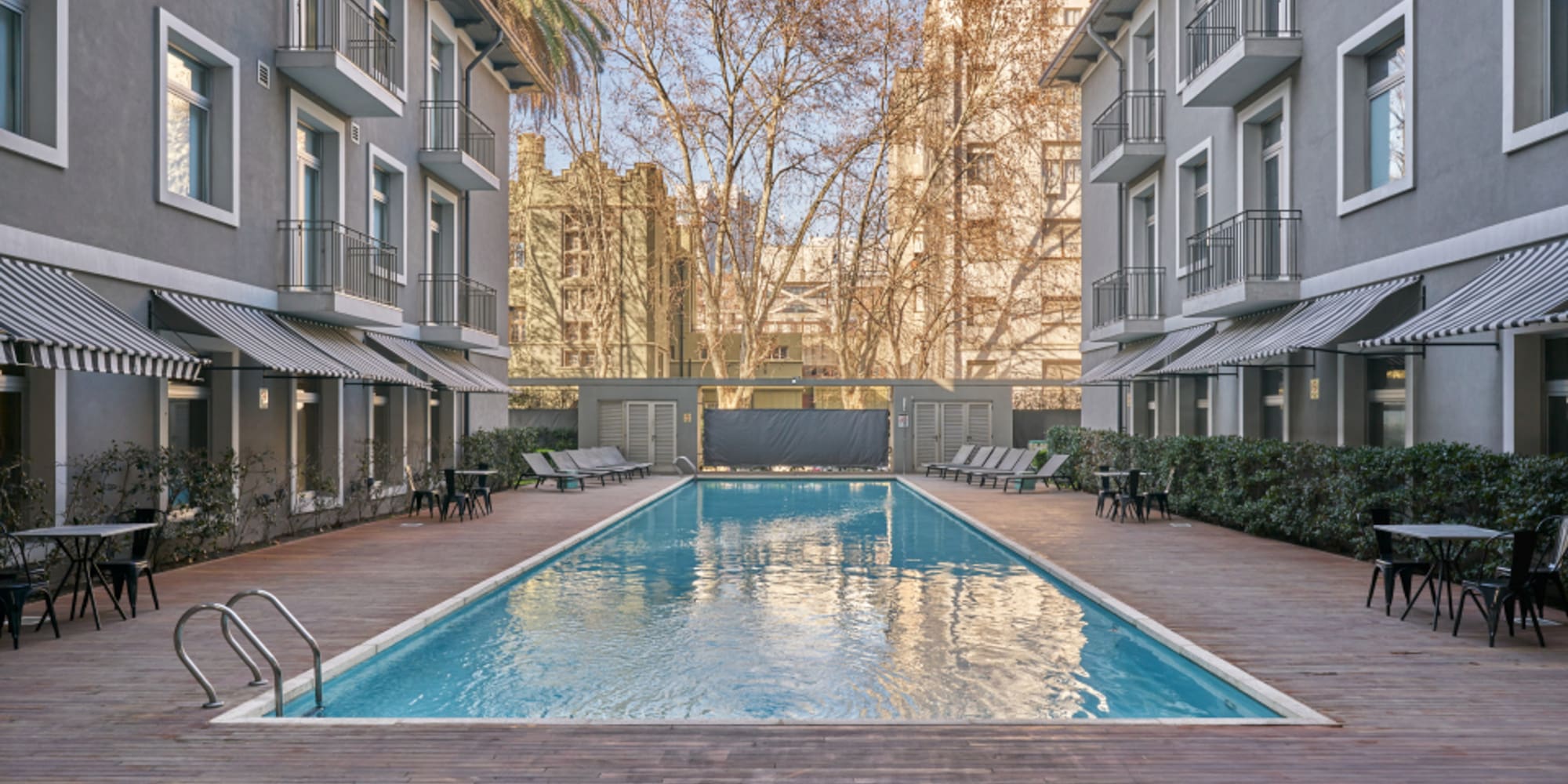 a swimming pool with chairs and trees in the background