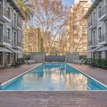 a swimming pool with chairs and trees in the background