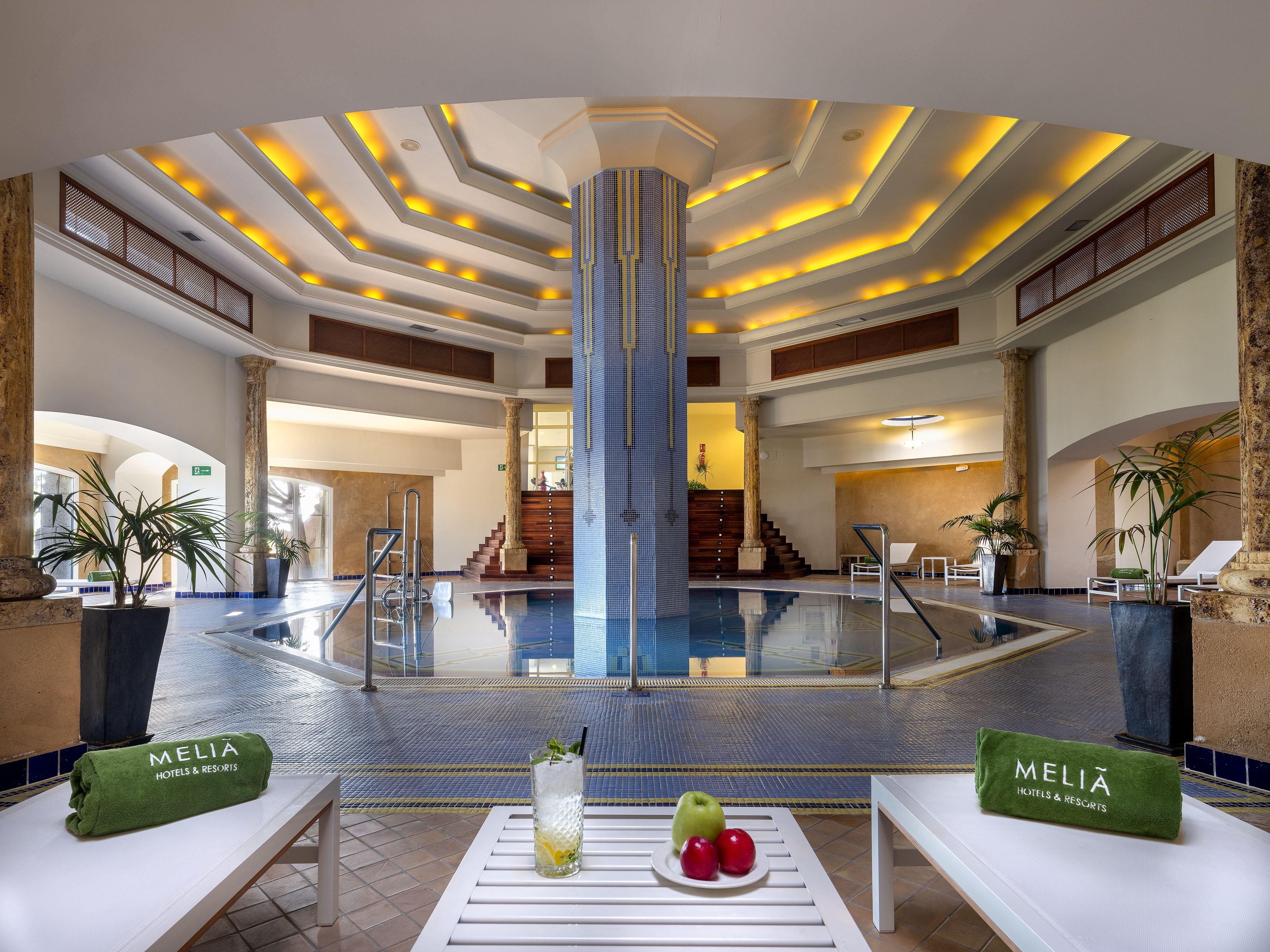 Meliã indoor spa pool with warm lighting, lounge chairs, and fruit.