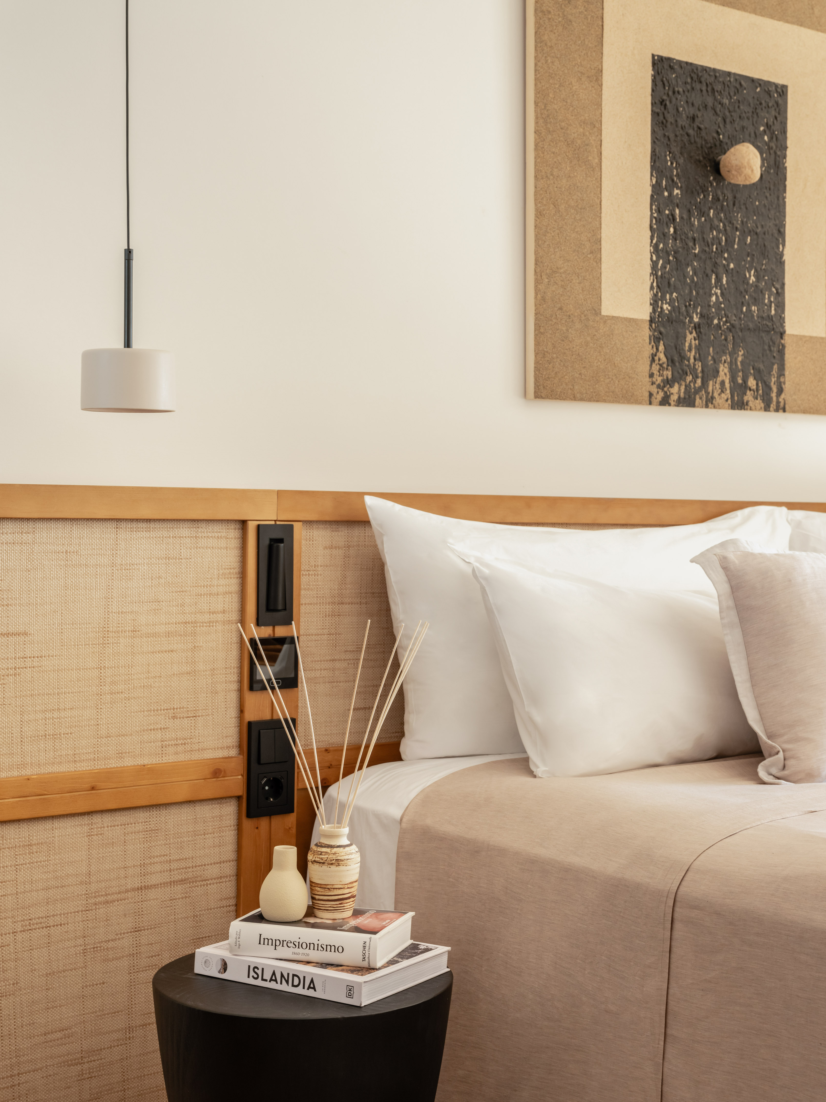 Neutral bedroom with woven headboard, white bed, and side table.