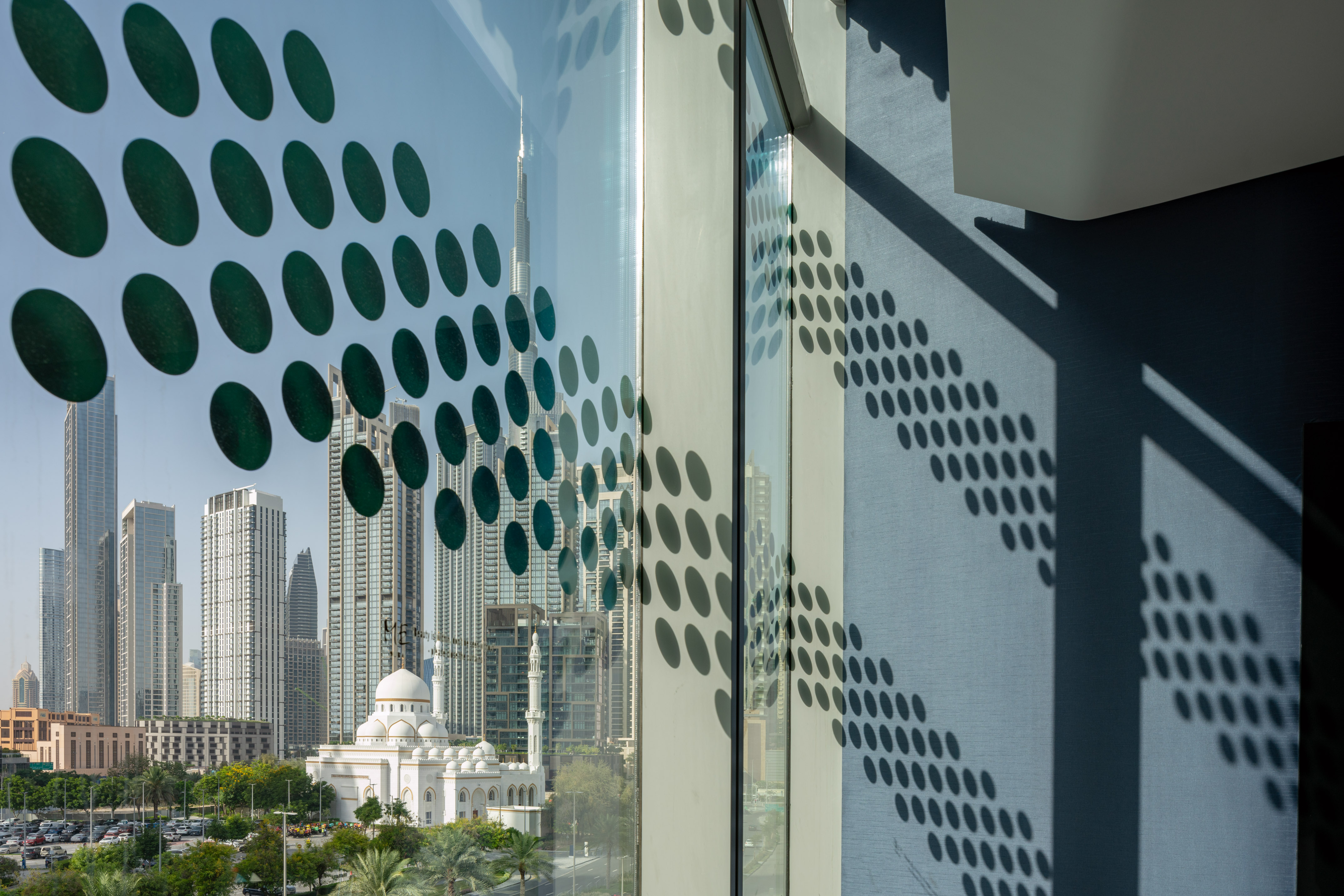 Dubai city view with mosque, Burj Khalifa reflection, and window dot patterns.