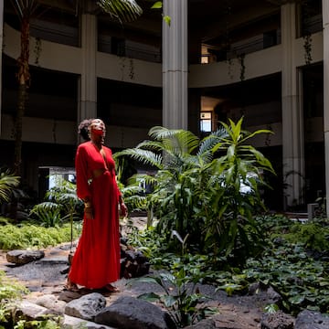 a woman in a red dress in a courtyard with plants