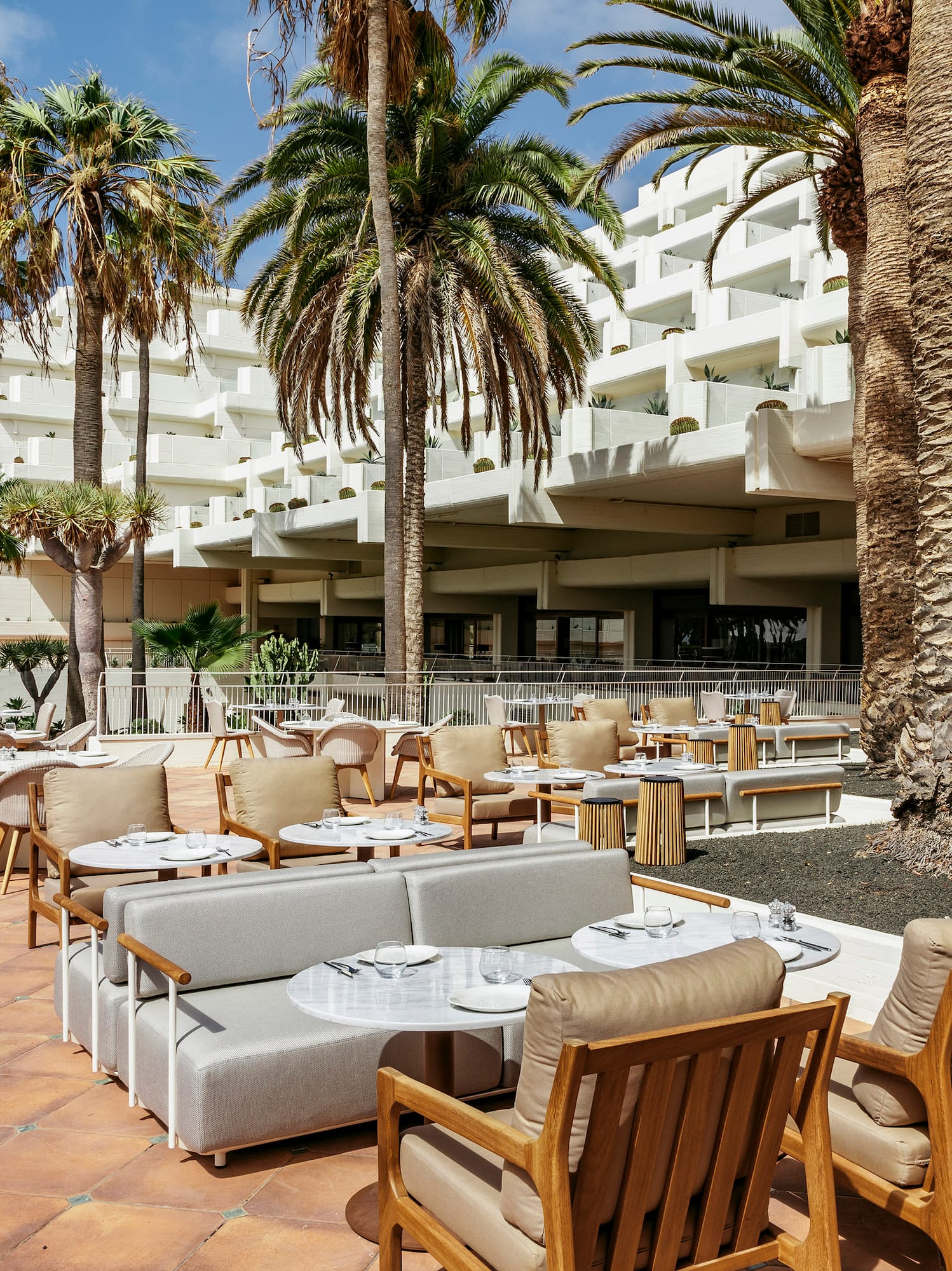 a patio with tables and chairs and palm trees
