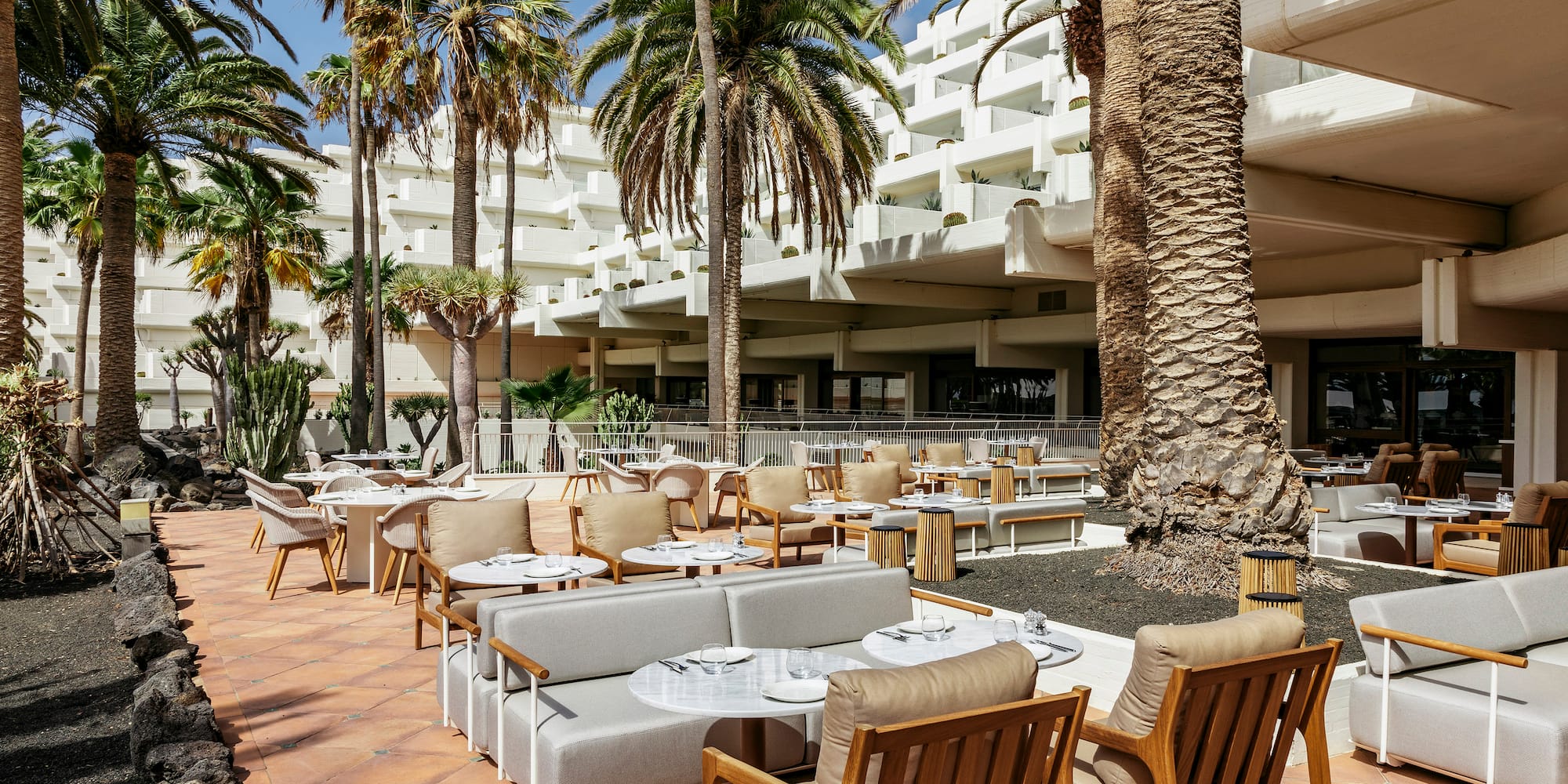 a patio with tables and chairs and palm trees