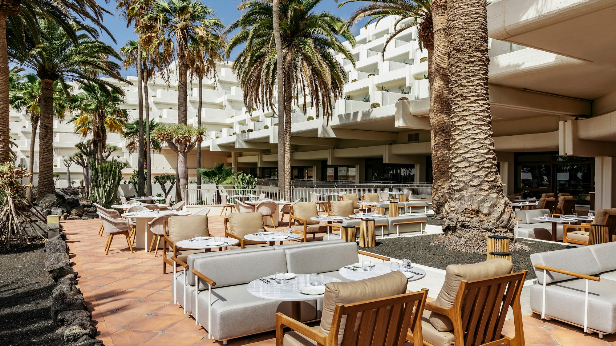 a patio with tables and chairs and palm trees