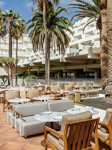 a patio with tables and chairs and palm trees