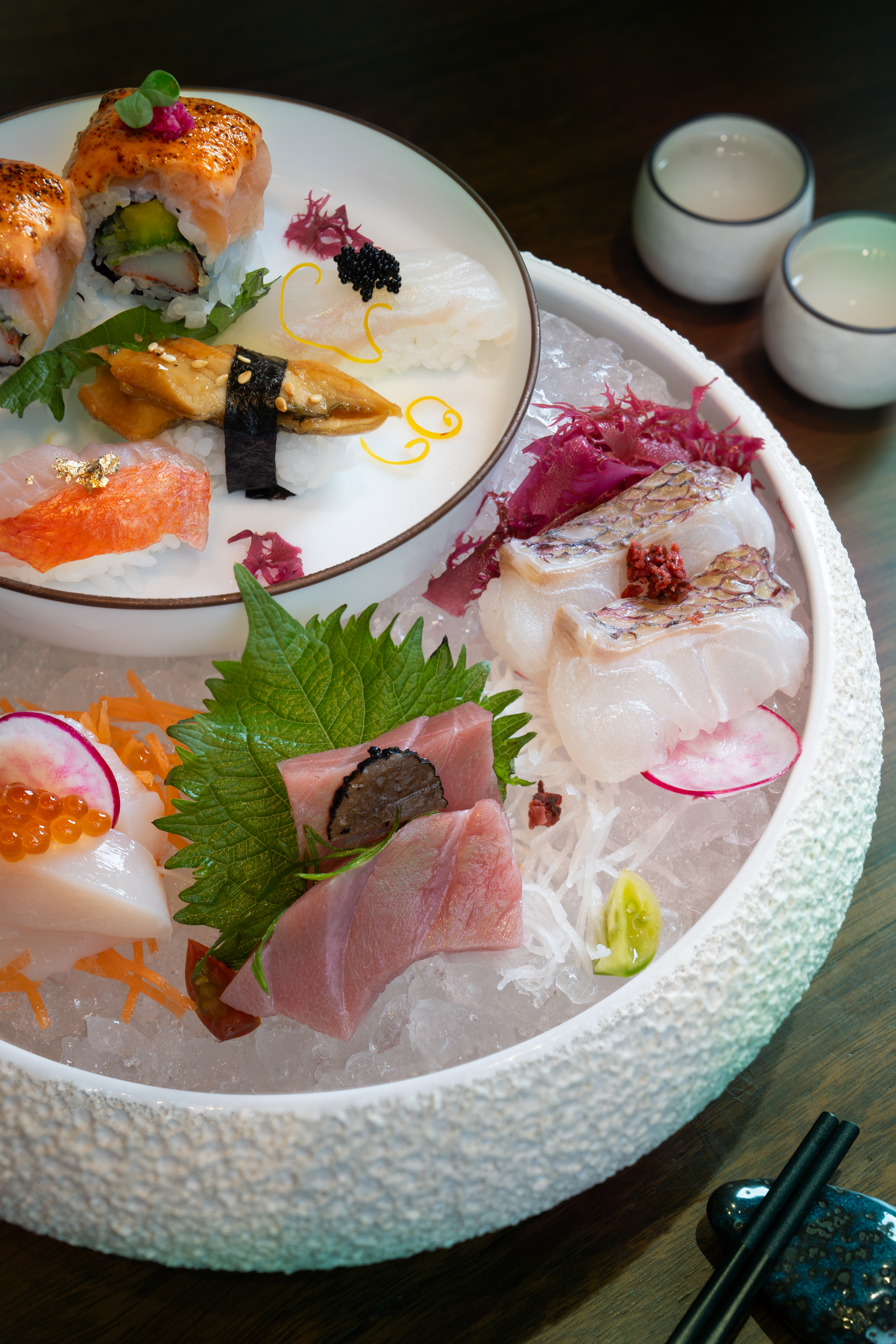 Japanese sushi & sashimi platter on ice: tuna, eel, scallops, and various rolls.
