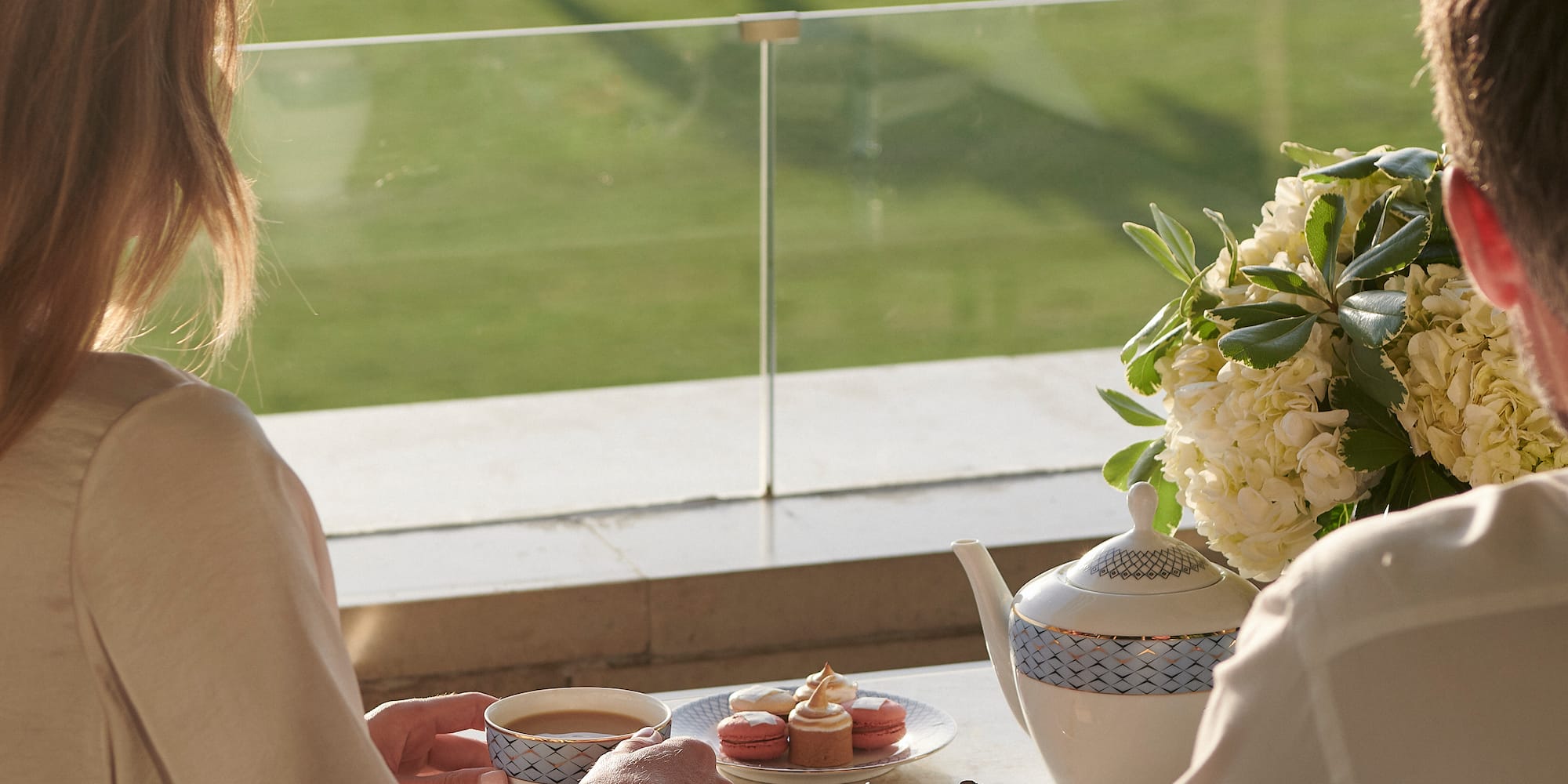 a couple of people sitting at a table with tea cups and desserts