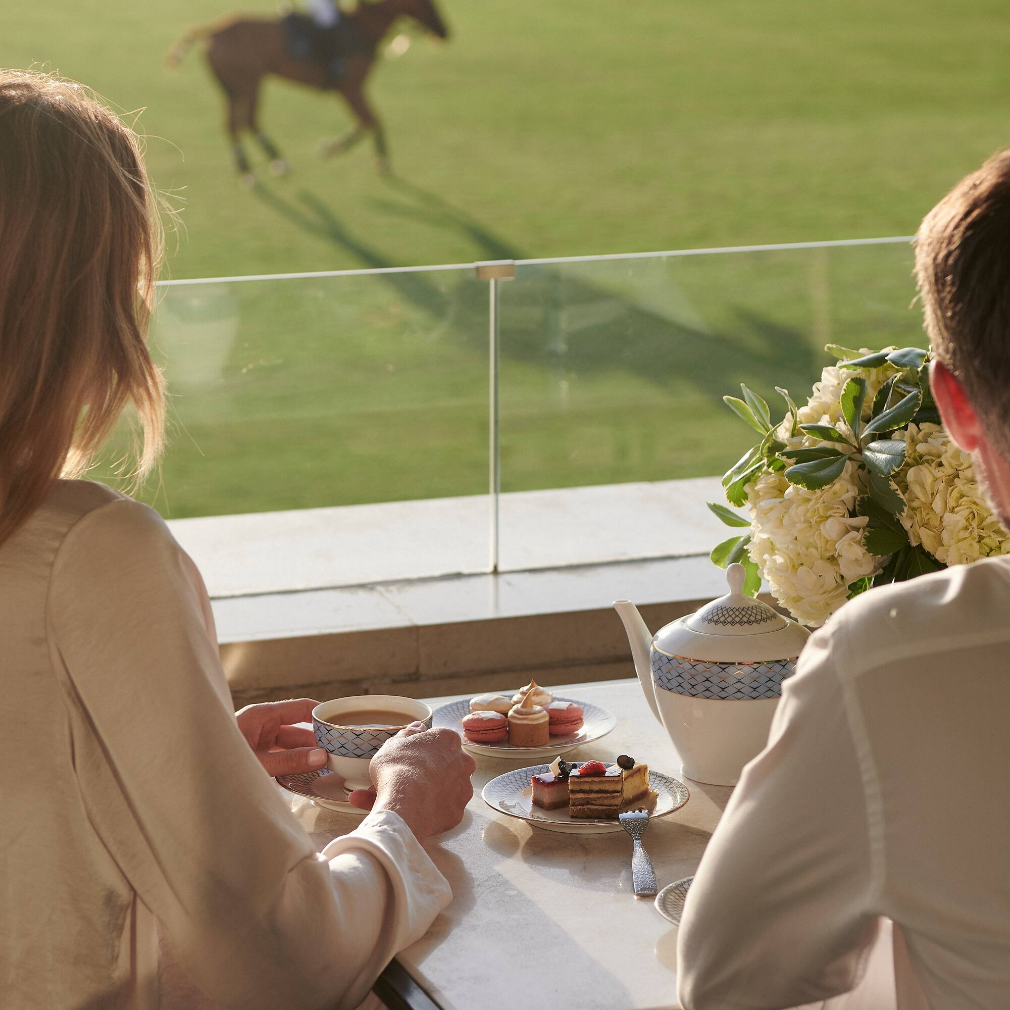 a couple of people sitting at a table with tea cups and desserts