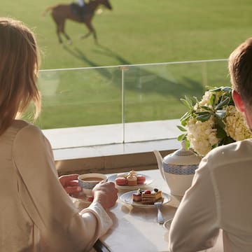 a couple of people sitting at a table with tea cups and desserts