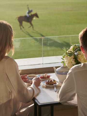 a couple of people sitting at a table with tea cups and desserts