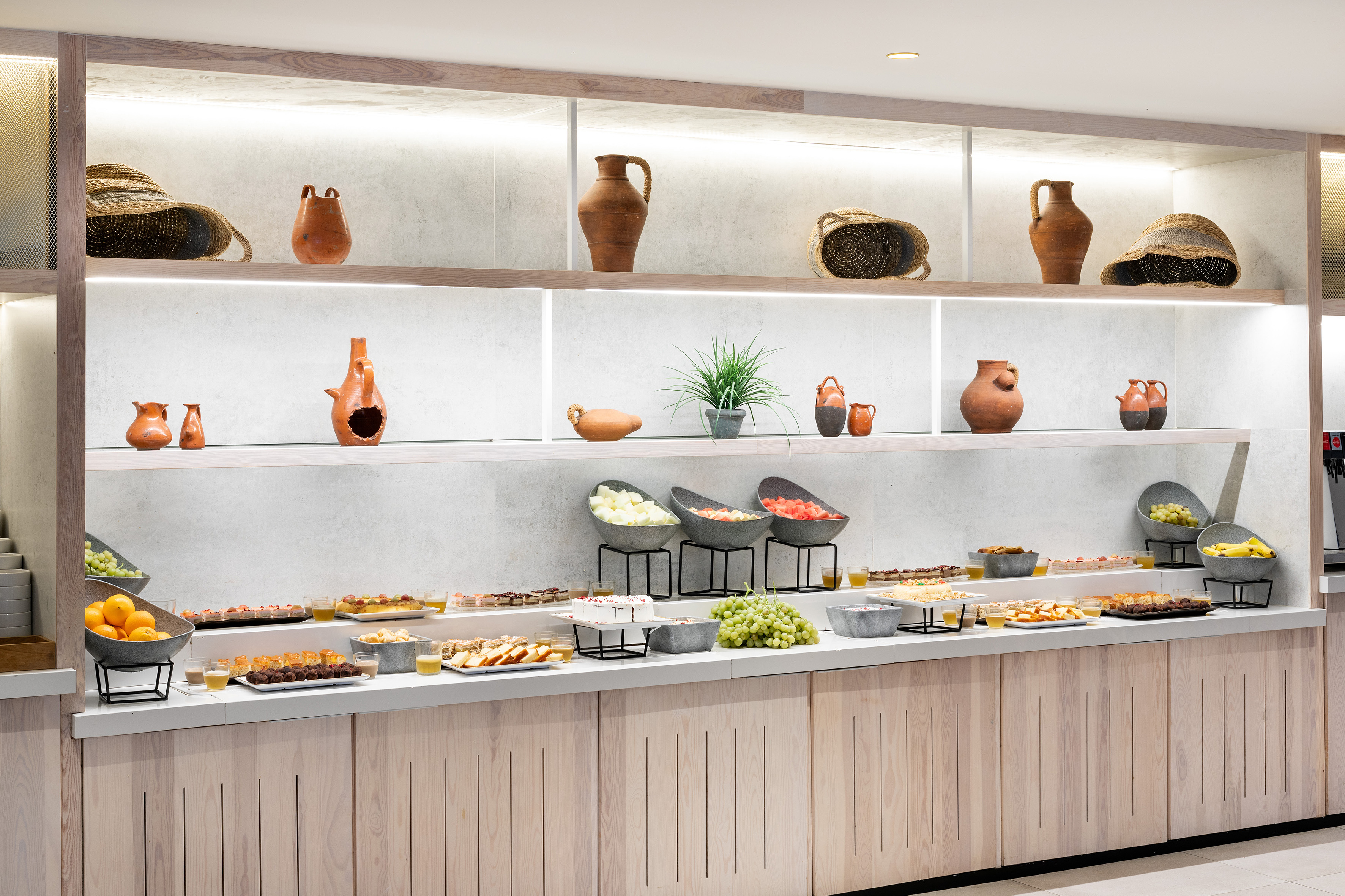 Vibrant hotel buffet with fresh fruit, pastries, and pottery decor.