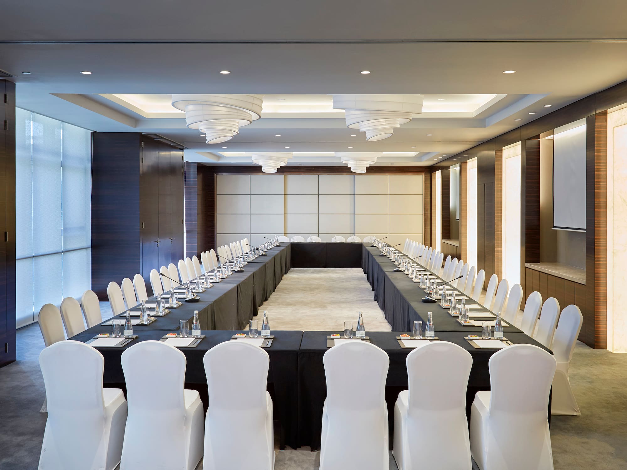 a long rectangular table with white chairs and black tablecloths