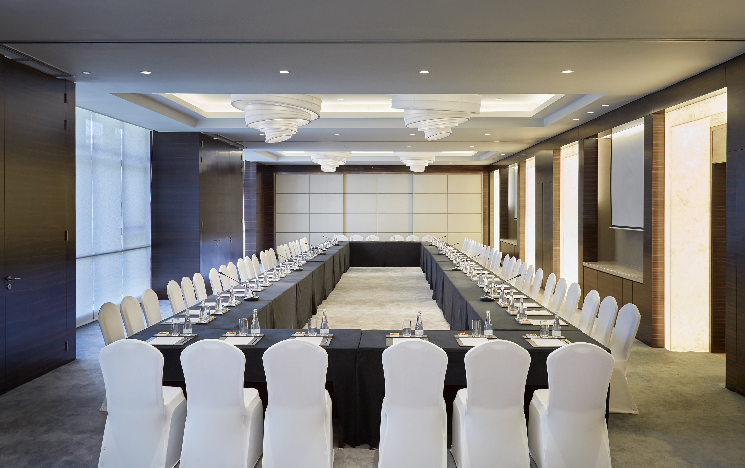 a long rectangular table with white chairs and black tablecloths