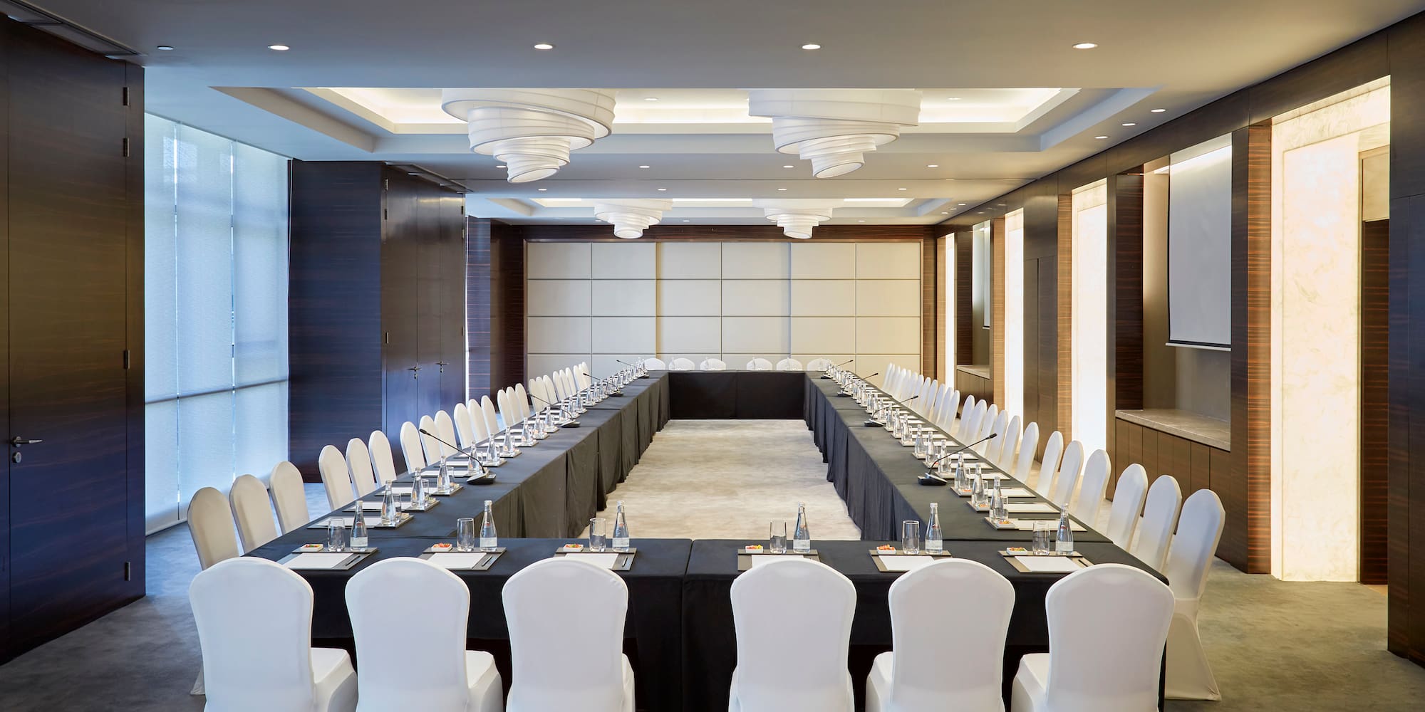 a long rectangular table with white chairs and black tablecloths