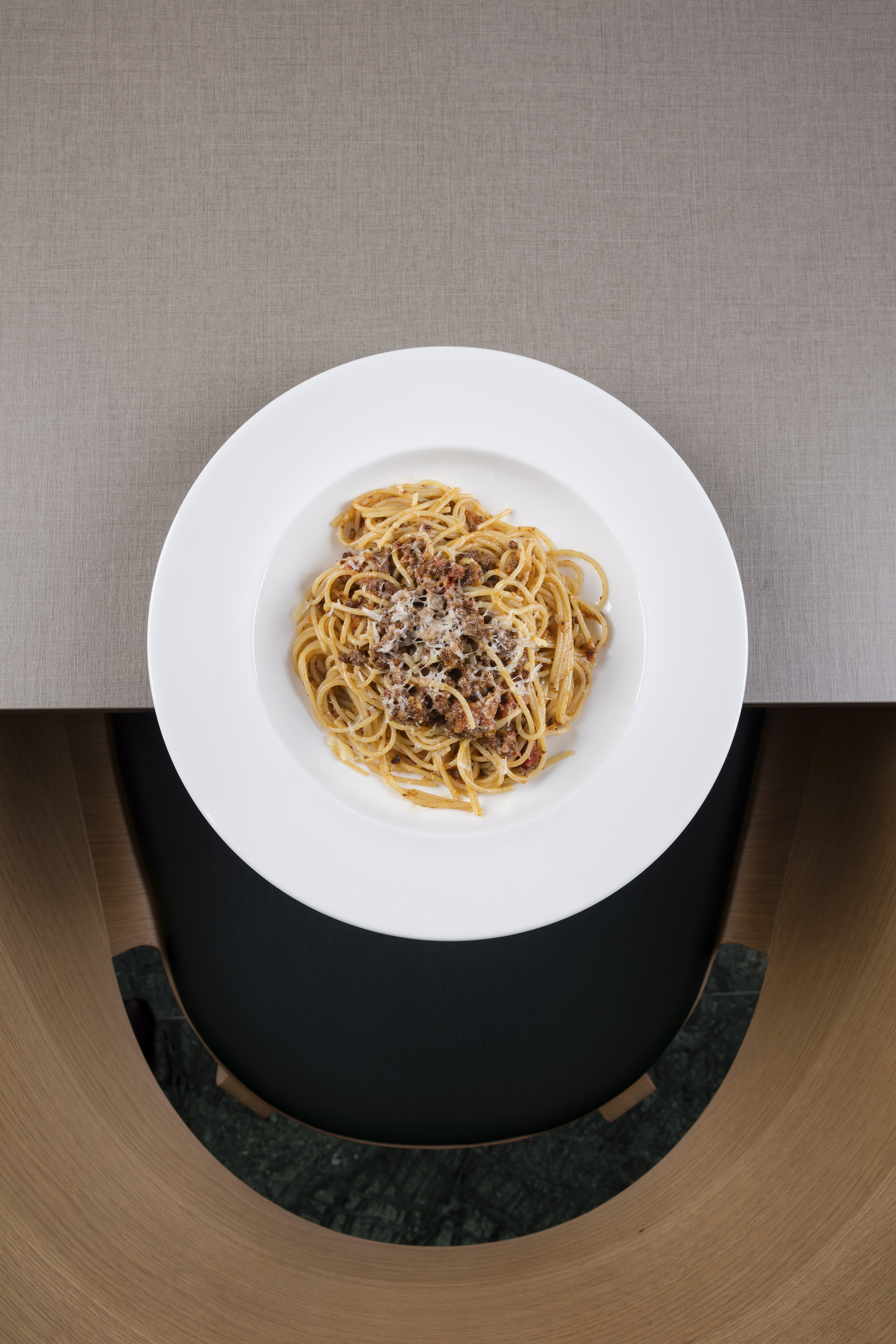 Italian spaghetti bolognese pasta with parmesan on a modern table.