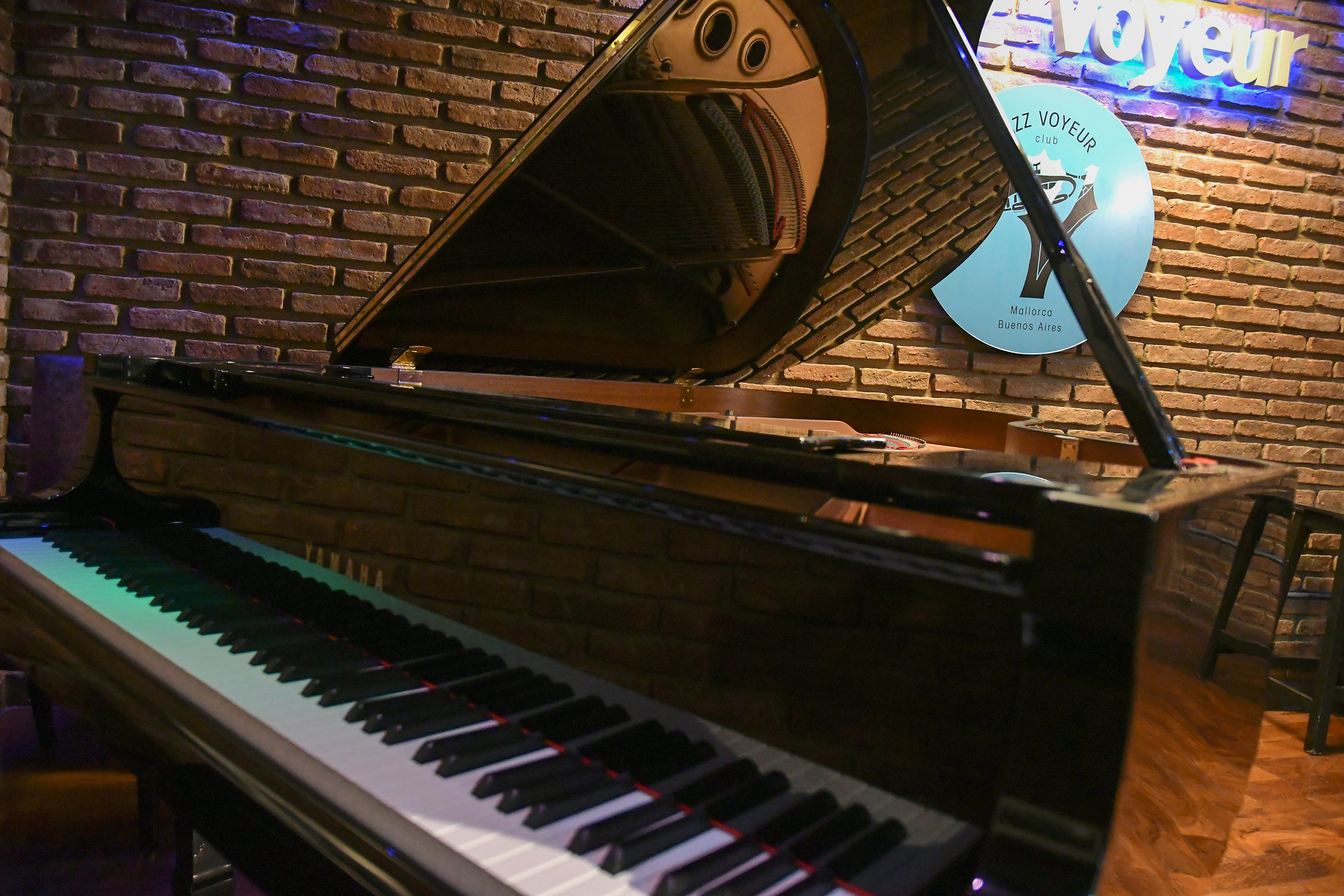 Black grand piano with open lid and keys in a jazz club, brick wall. - Jazz Voyeur Club - Melia Recoleta Plaza, Buenos Aires