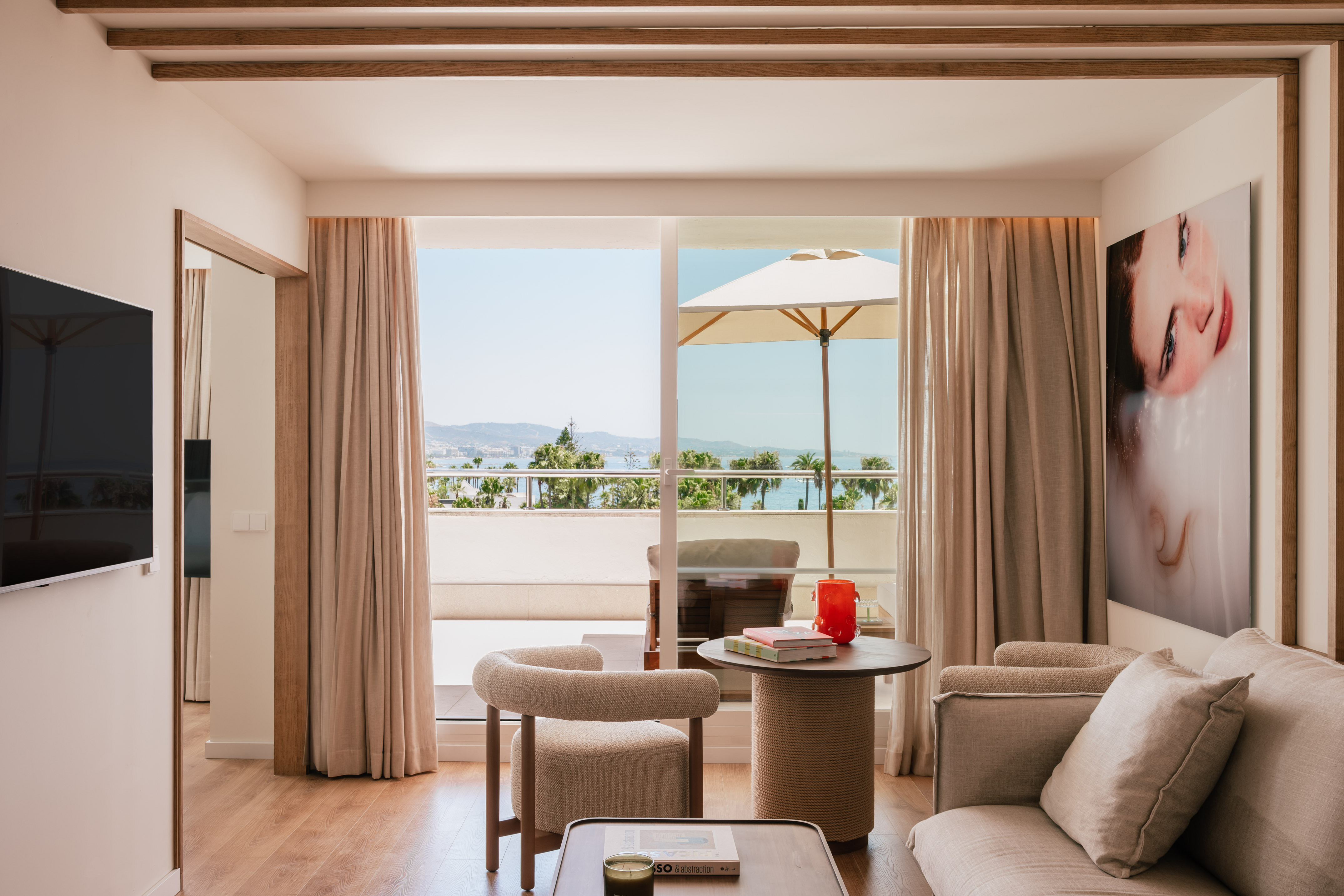Bright modern hotel suite with sea view balcony and contemporary decor.