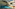Indoor swimming pool under glass roof, blue tiled water, natural light.