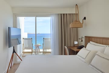 a room with a bed and a television and a view of the ocean