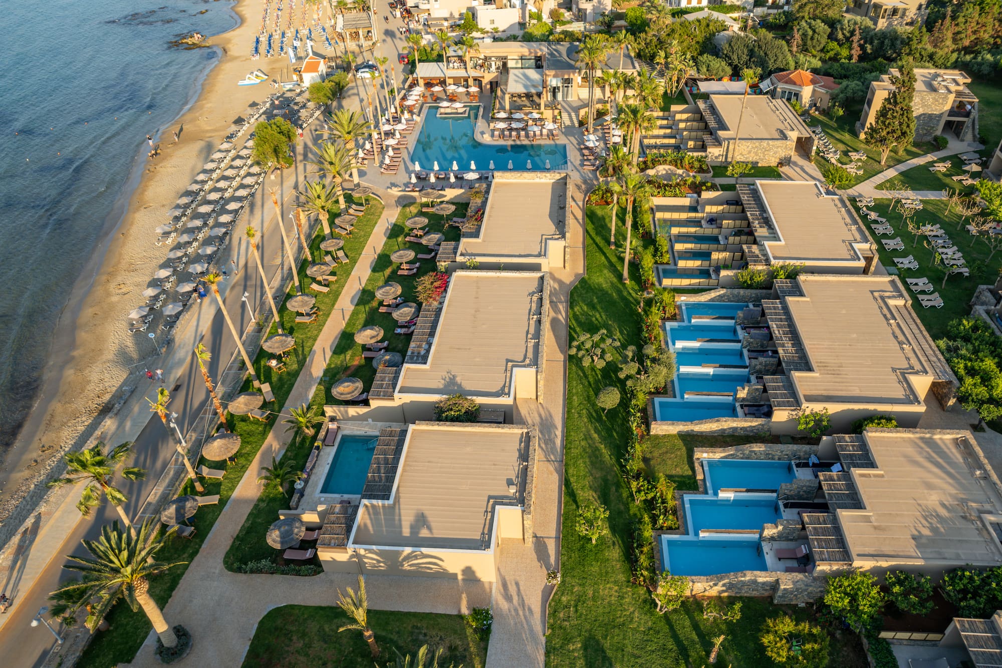 Luxury beach resort with multiple swimming pools, private pools, and palm trees.