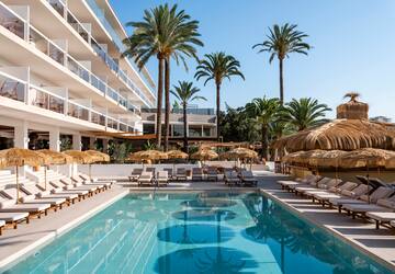 a pool with lounge chairs and umbrellas in front of a building