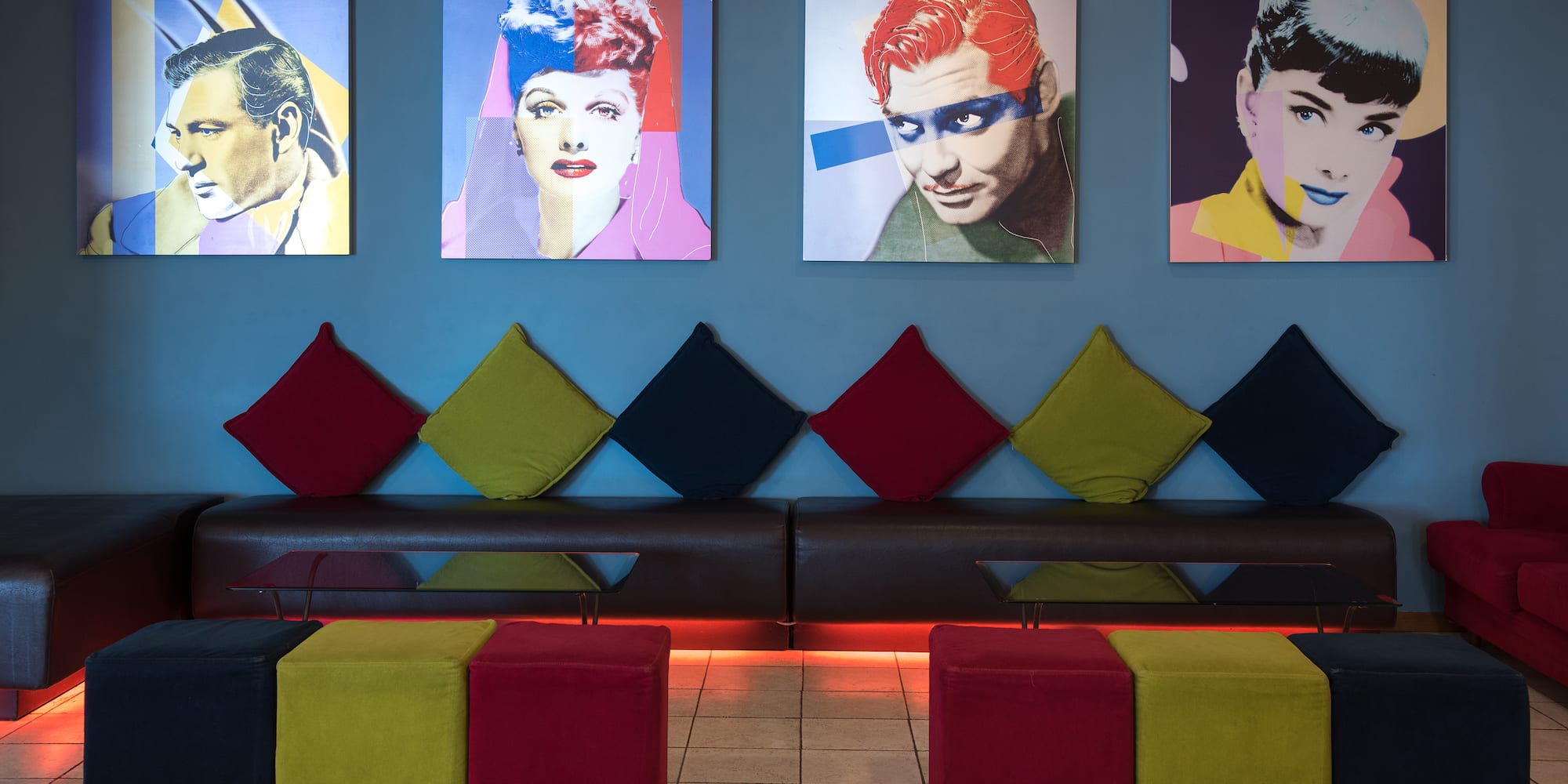 a room with a couch and pictures of people on the wall