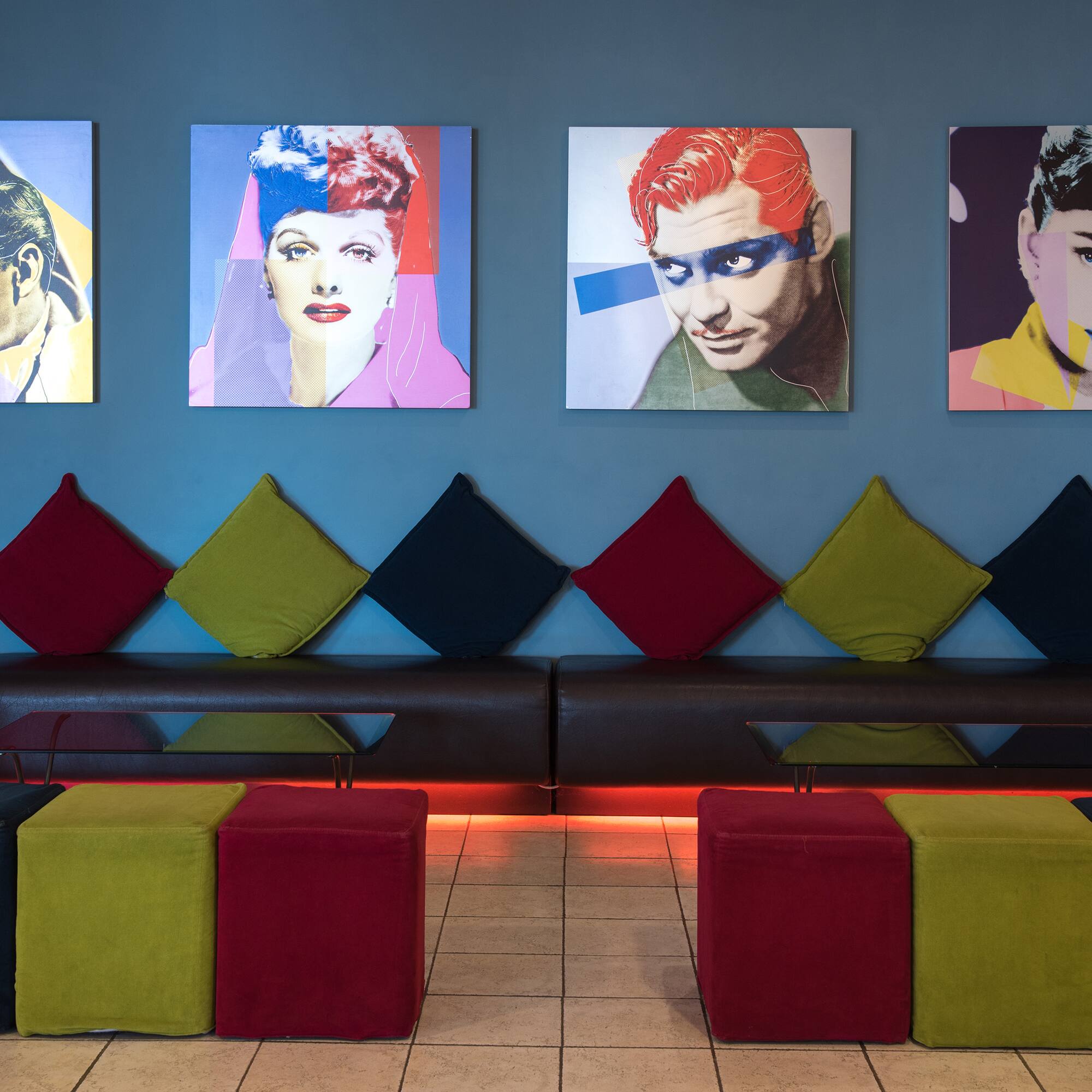 a room with a couch and pictures of people on the wall