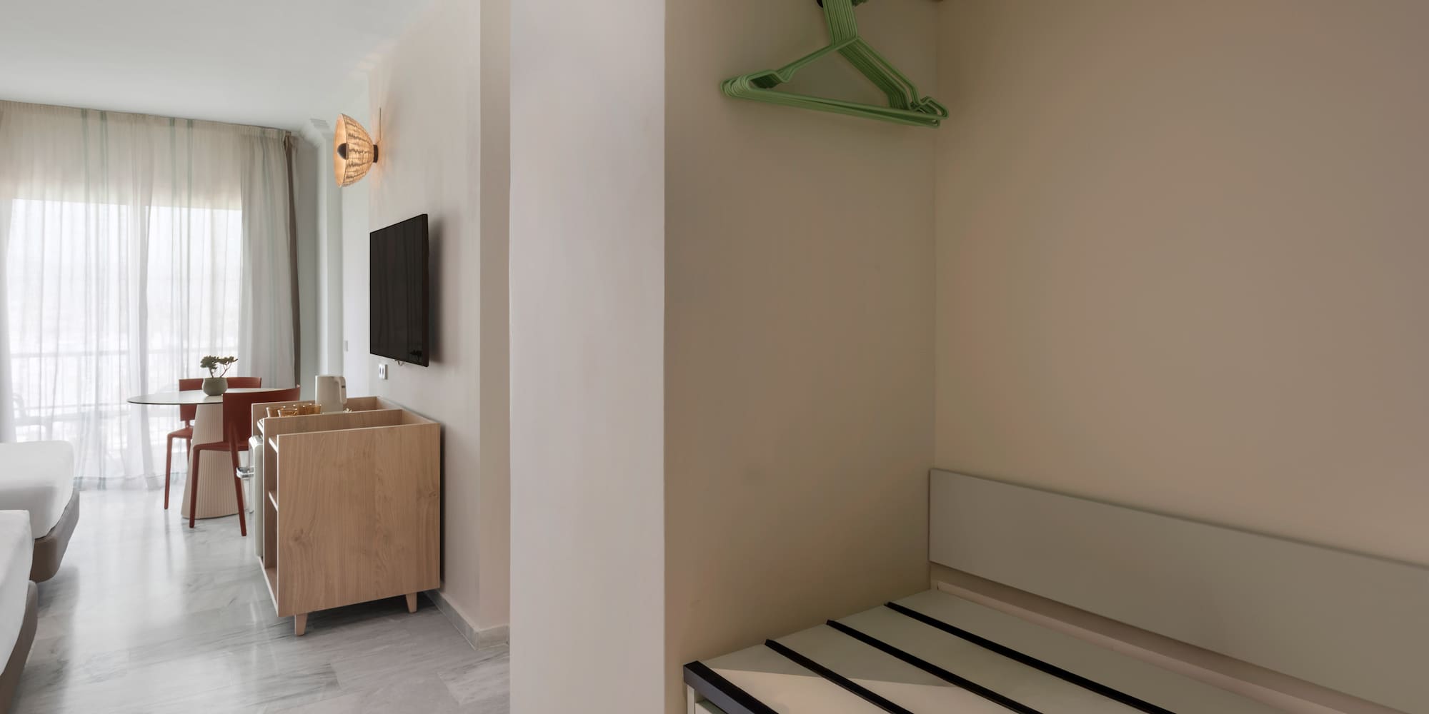 Hotel suite interior: open closet, luggage storage, bright living space.