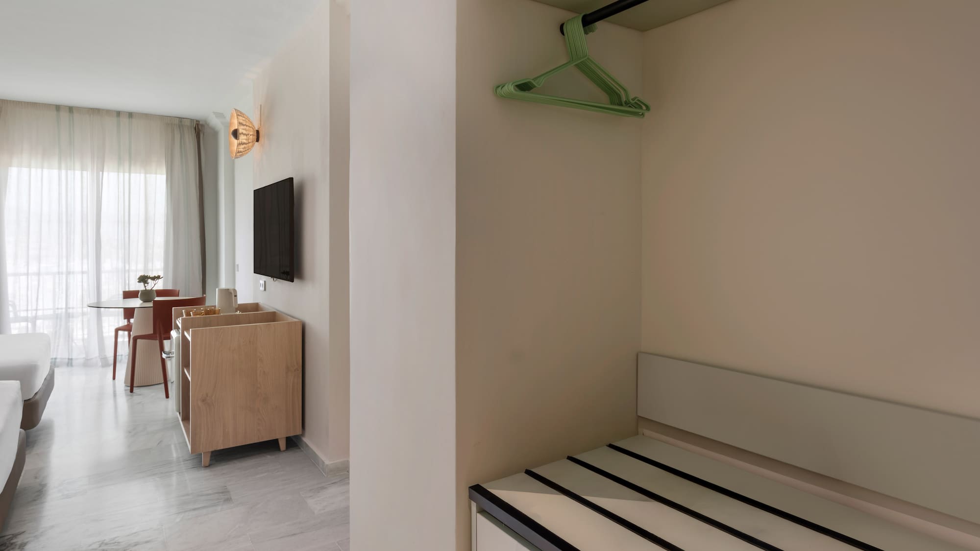 Hotel suite interior: open closet, luggage storage, bright living space.