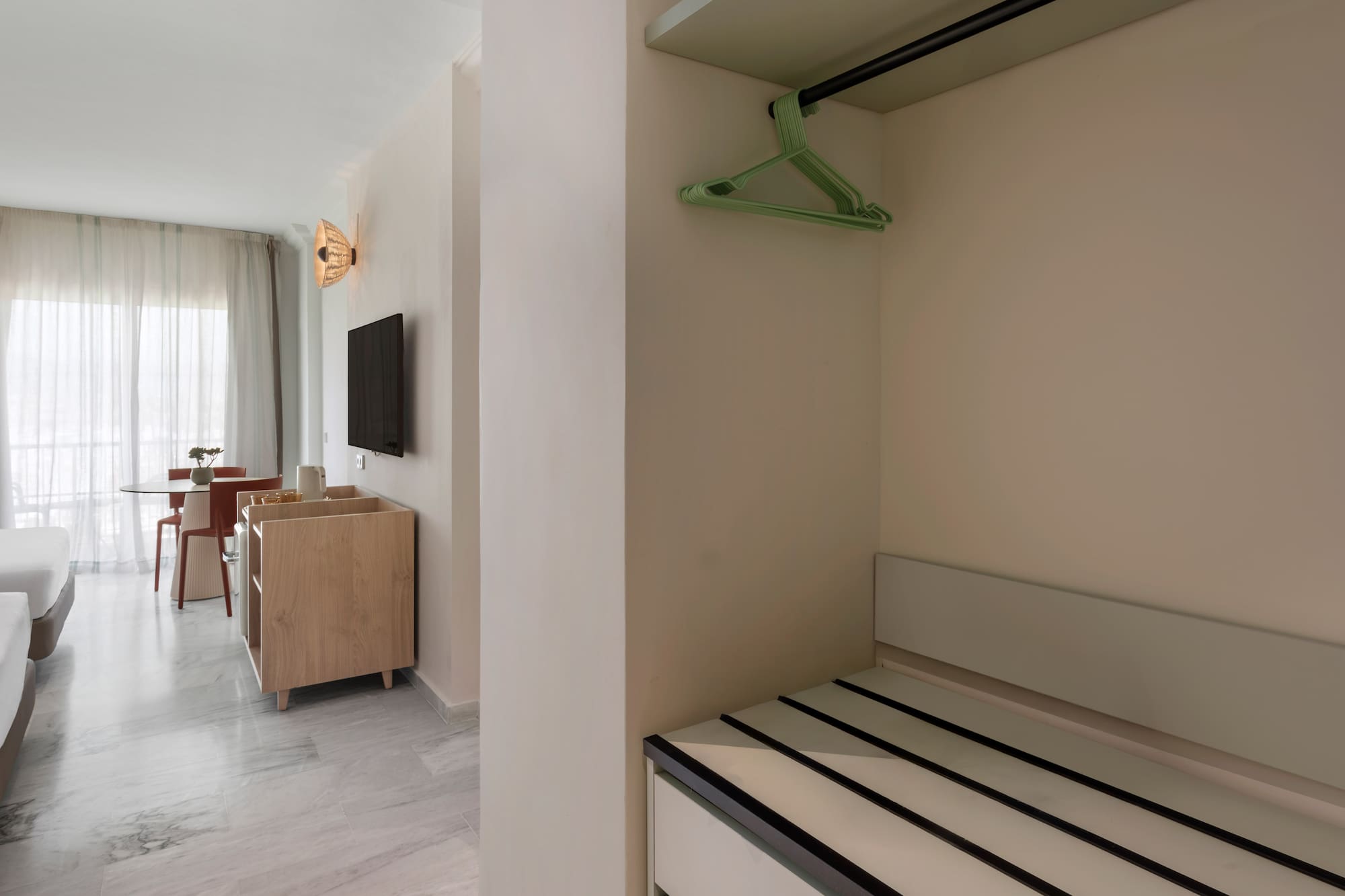 Hotel suite interior: open closet, luggage storage, bright living space.