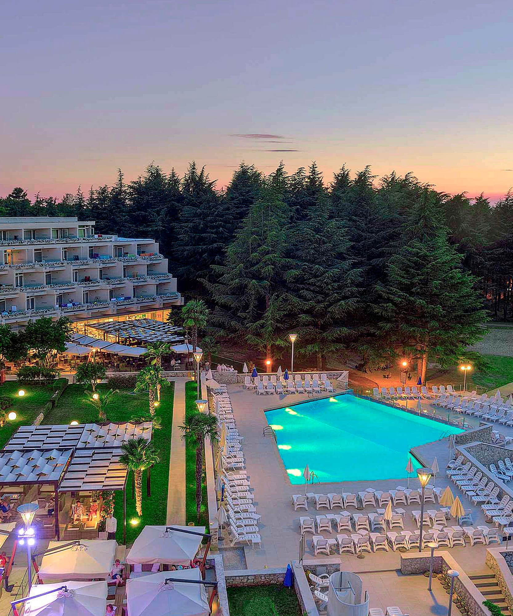 a pool and a hotel with trees in the background