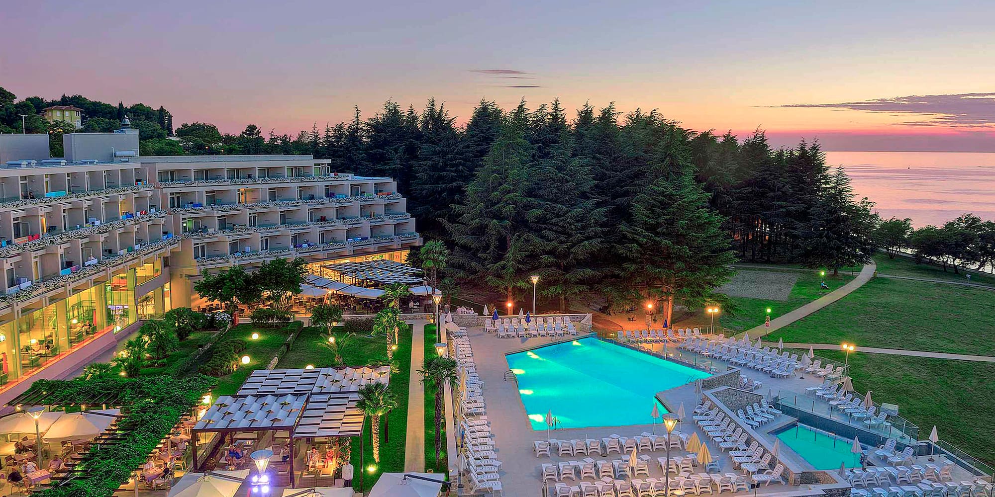 a pool and a hotel with trees in the background