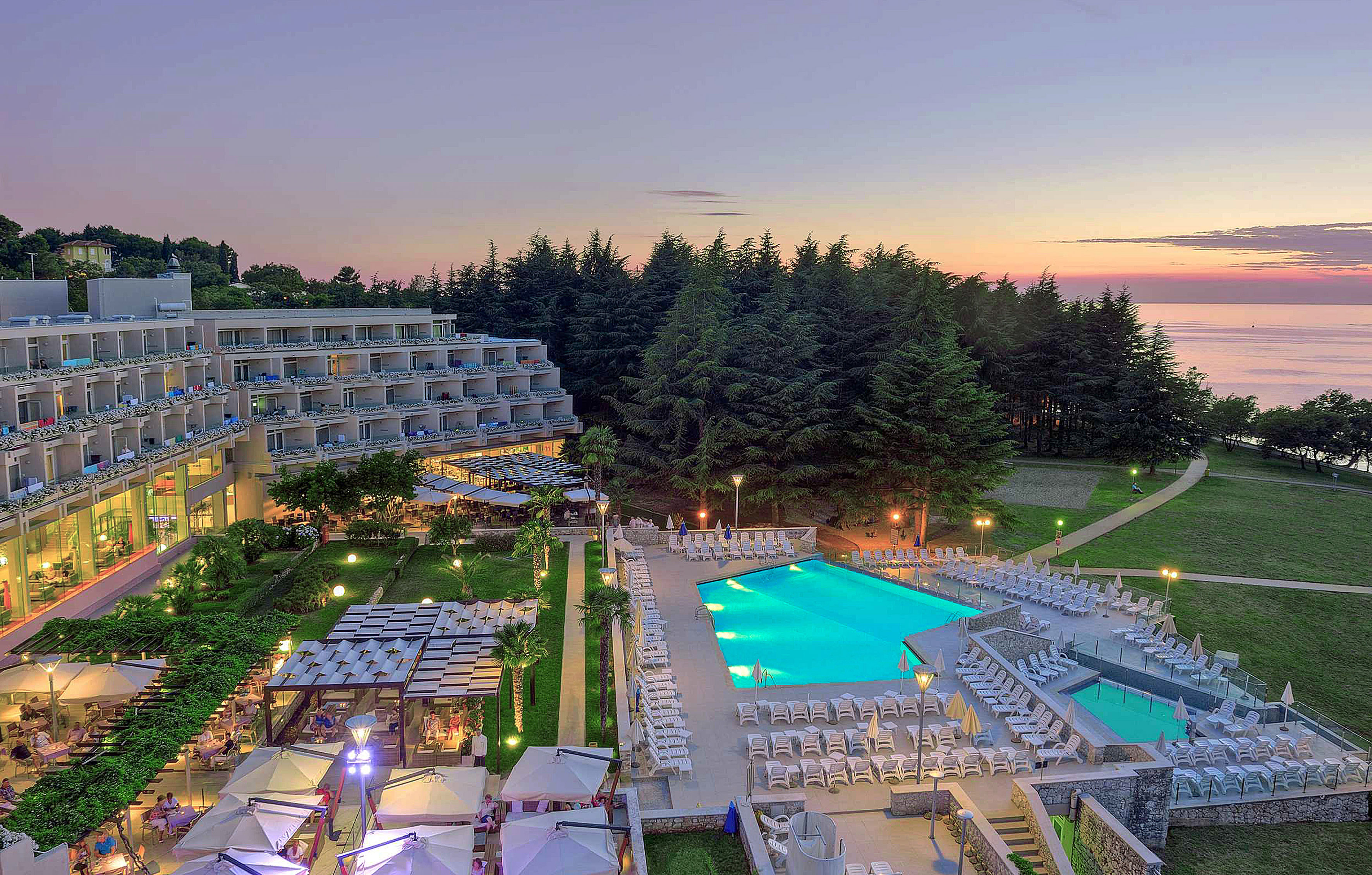 a pool and a hotel with trees in the background