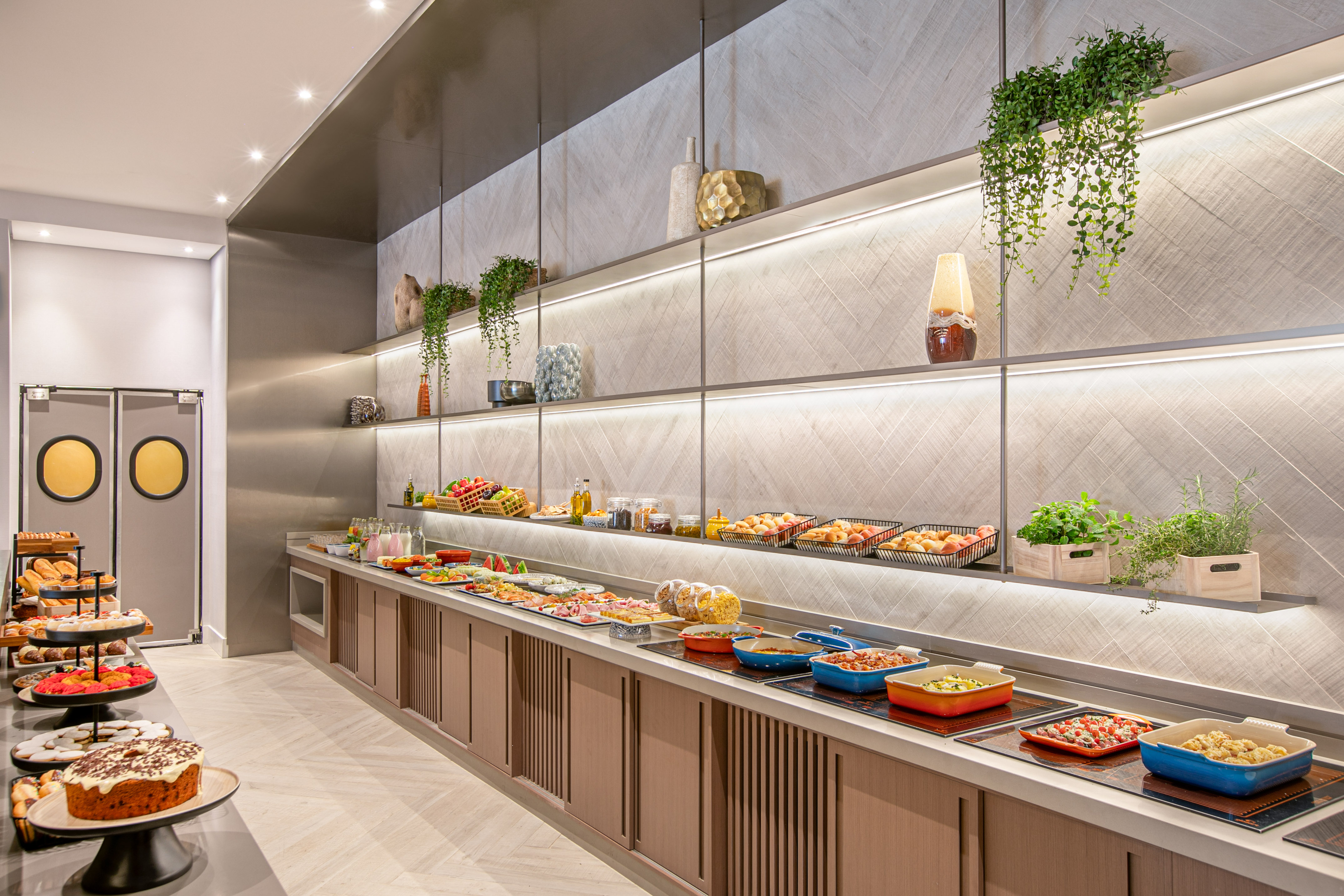 Modern hotel breakfast buffet featuring hot dishes, pastries, and fresh fruit.