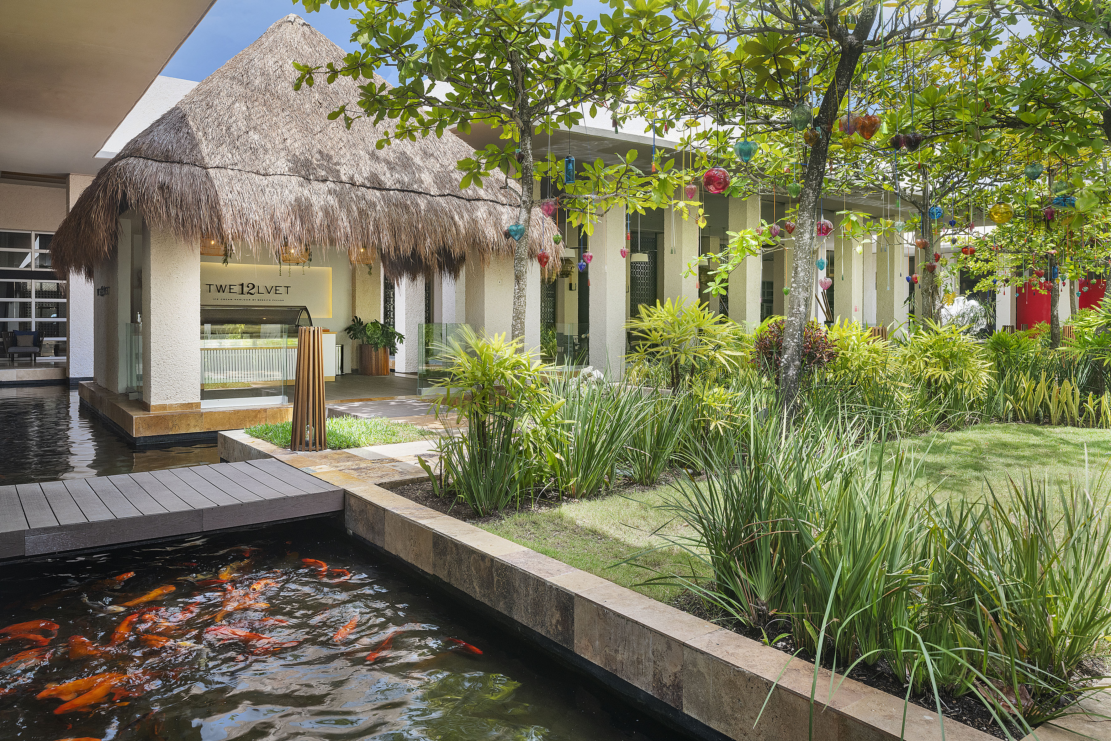 Thatched ice cream parlour, koi pond, tropical garden with decorated trees.