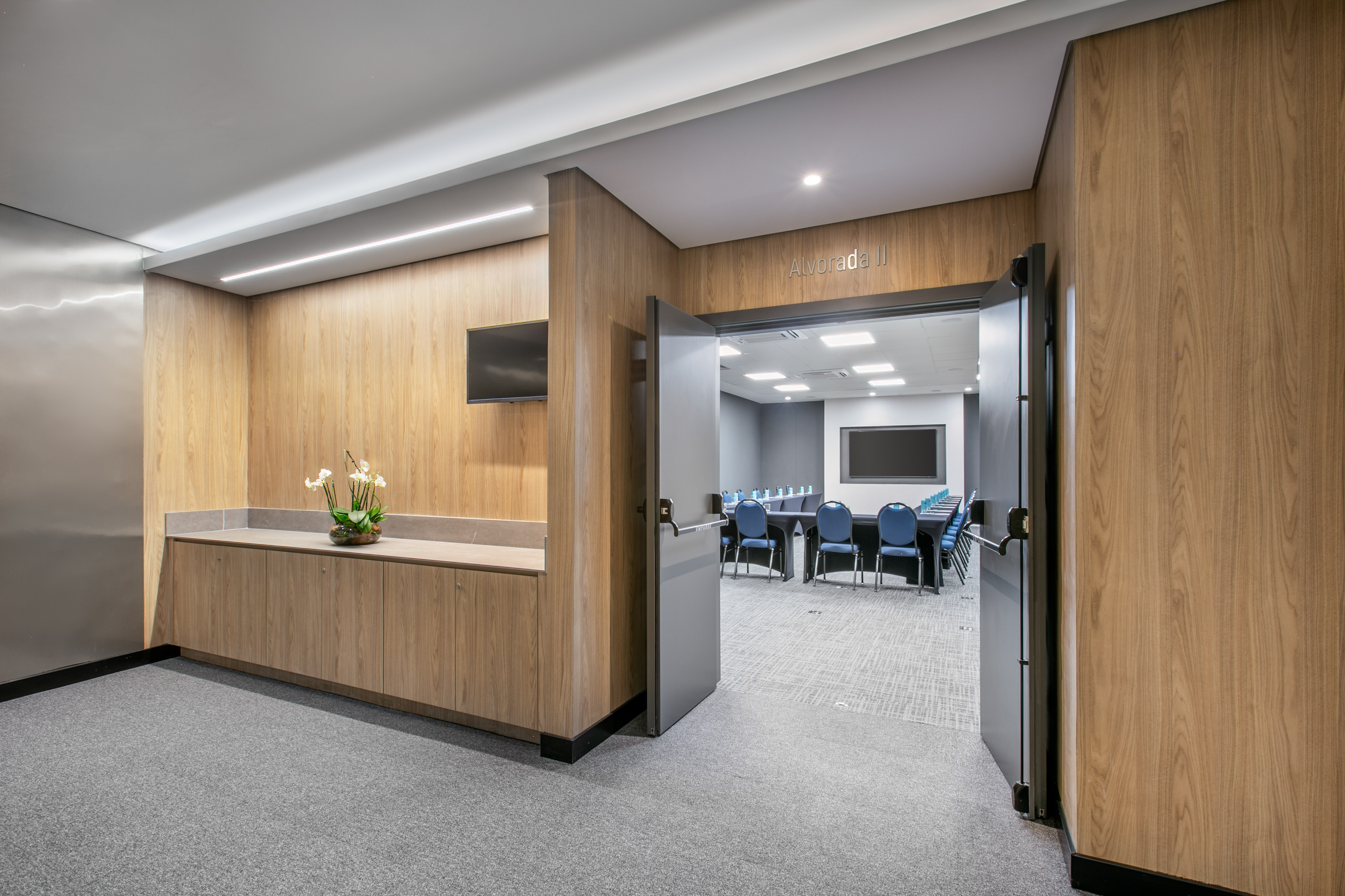 Modern Alvorada II conference room entrance from wood-paneled hallway.